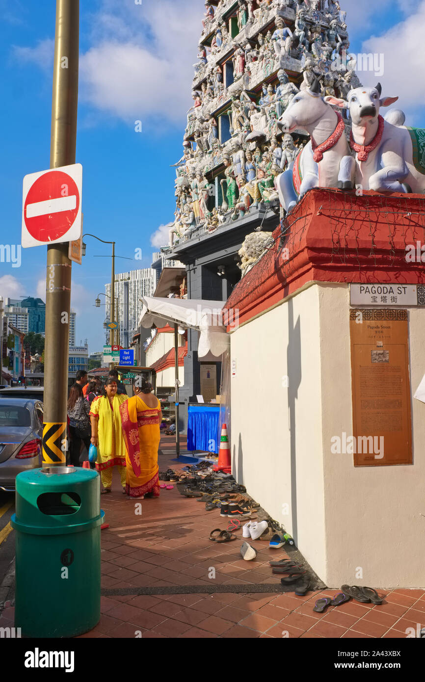 Sari-placcati donne Indù stand al di fuori del Tempio di Sri Mariamman, South Beach Rd., Chinatown, Singapore, un gopuram o porta torre innalzarsi al di sopra del suo ingresso Foto Stock