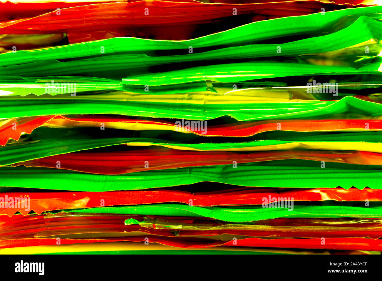 Pila di rosso, giallo e verde in plastica Lamina di confezioni di merendine. Vista ravvicinata. Cibo sano concetto di riciclaggio. Foto Stock