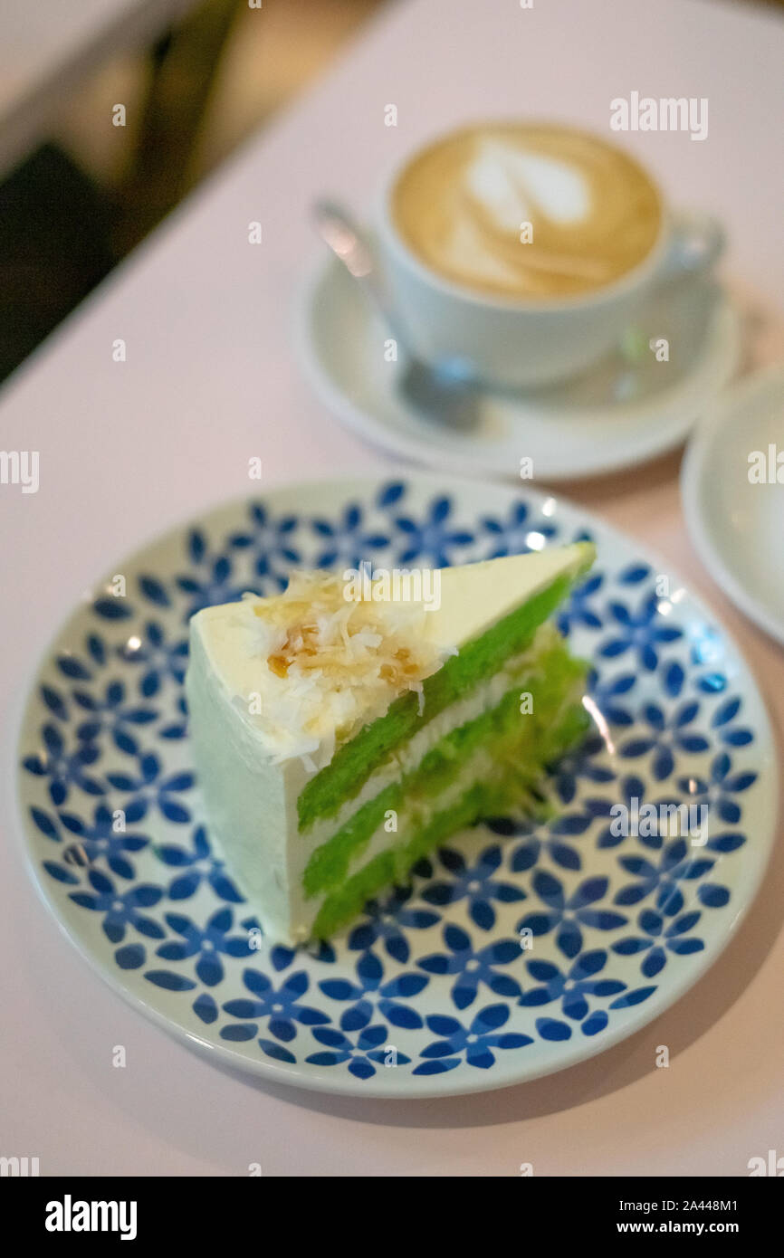 Una fetta di torta al cioccolato sulla piastra. Gula Melaka torta in colore verde. Torta di caffè tè del concetto di tempo. Foto Stock