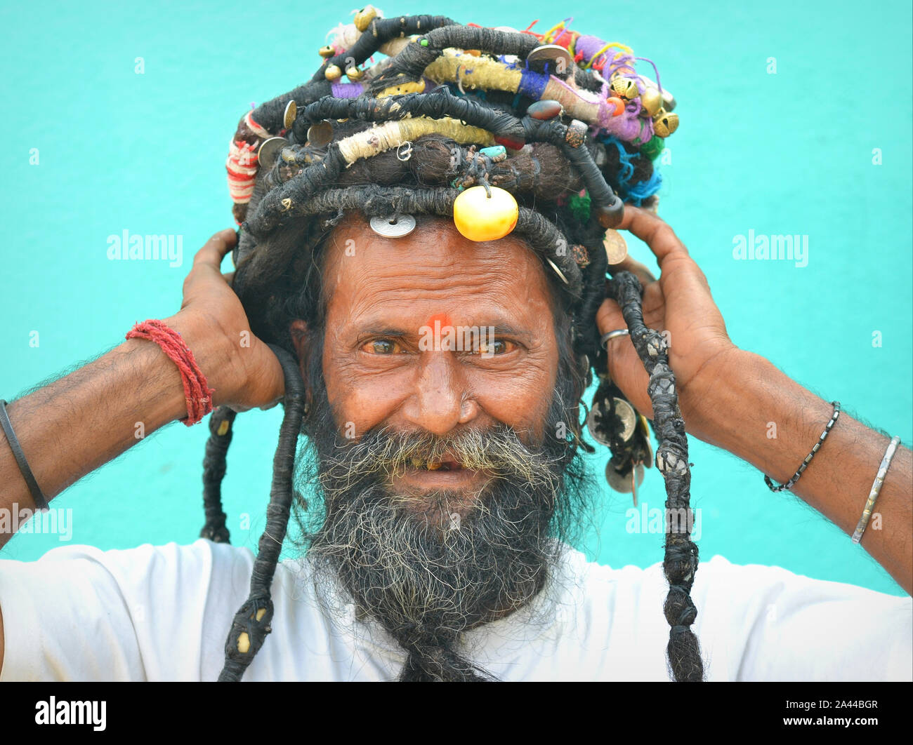 Yogi indiano mostra il suo arrotolamento a dreadlocks con perle e monete pone per la fotocamera. Foto Stock