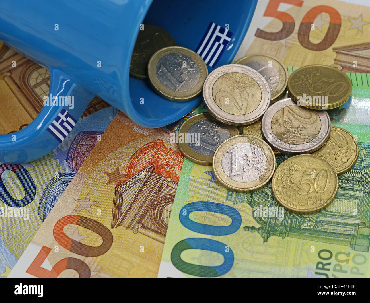 Monete metalliche in euro cadere fuori della coppa greca sulle banconote in euro background. concetto di finanza Foto Stock