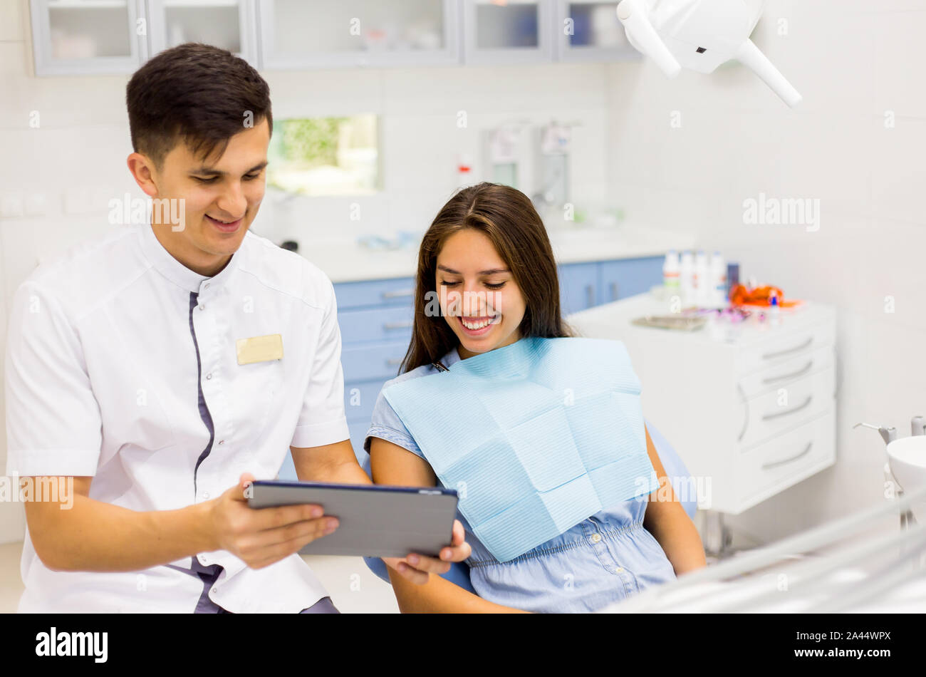 Giovani dentista in studio dentistico a parlare con la paziente di sesso femminile e la preparazione per il trattamento. Foto Stock