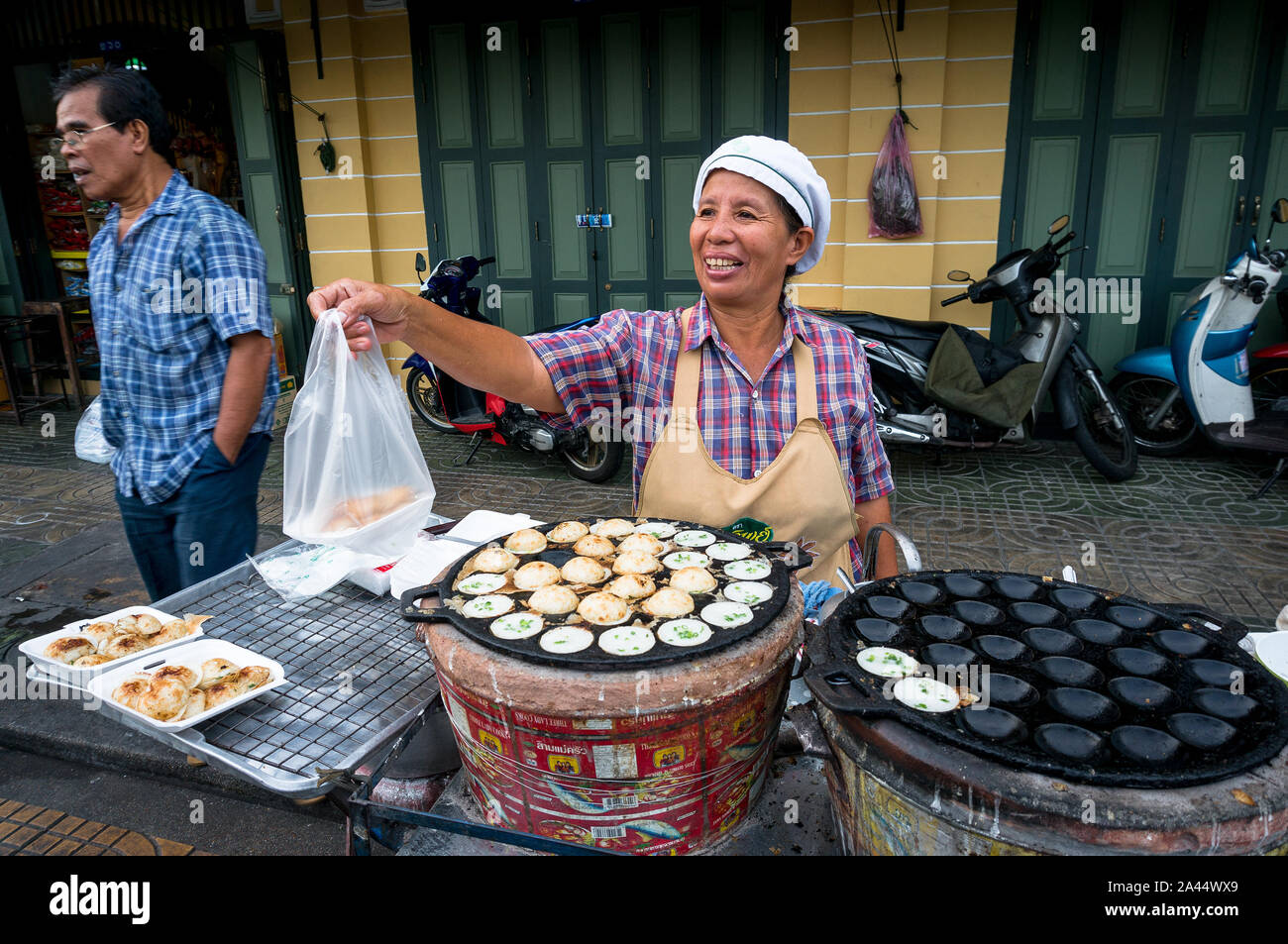 Bangkok, Tailandia - 24 Dic, 2015: Street fornitore di prodotti alimentari in vendita di Bangkok tailandese tradizionale Kanom alimentare coke, crema di noce di cocco torta. Foto Stock