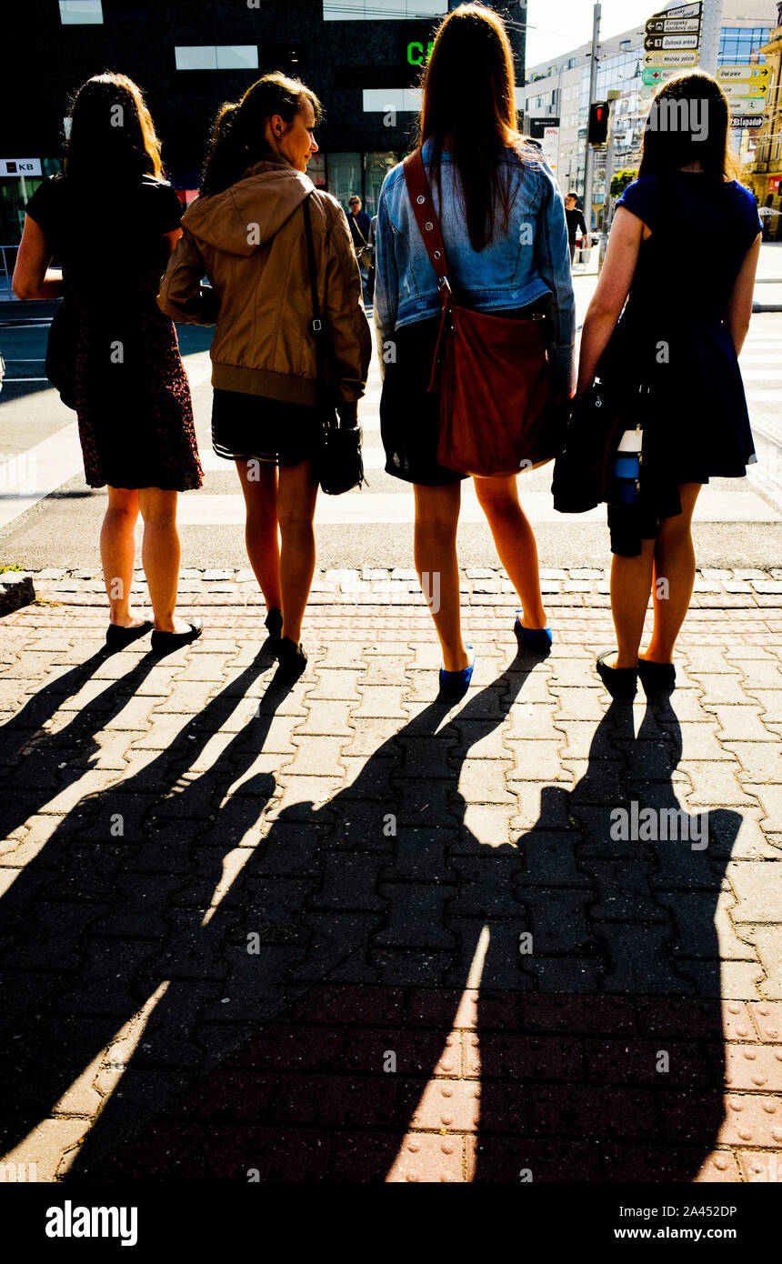 Le quattro ragazze in attesa presso la croce di strada per un semaforo verde per attivare Foto Stock