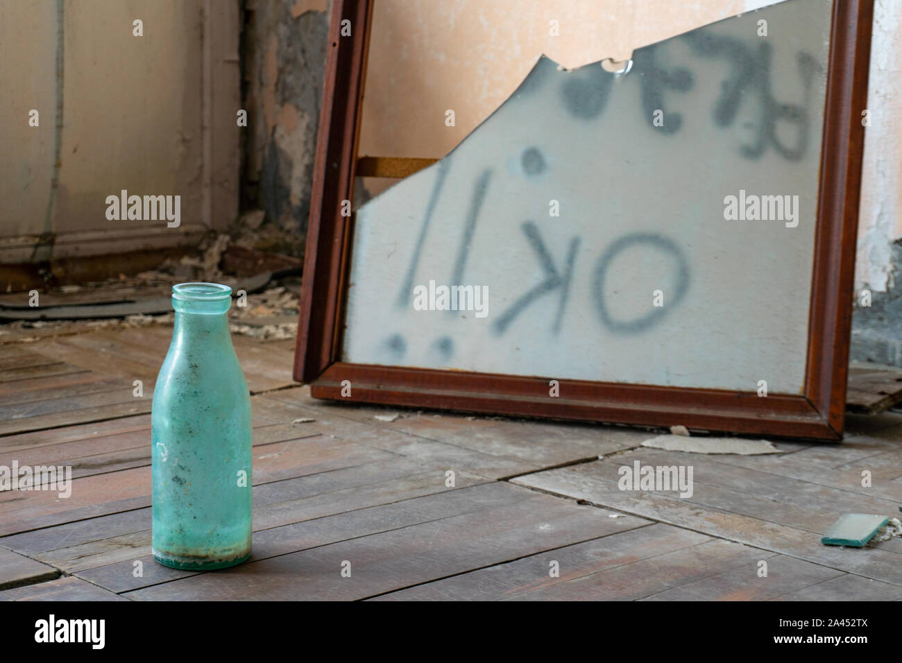 Concetto shot. bottiglia vuota ed inversione di segno OK in specchio rotto. Abbandonato edificio grunge. Foto Stock