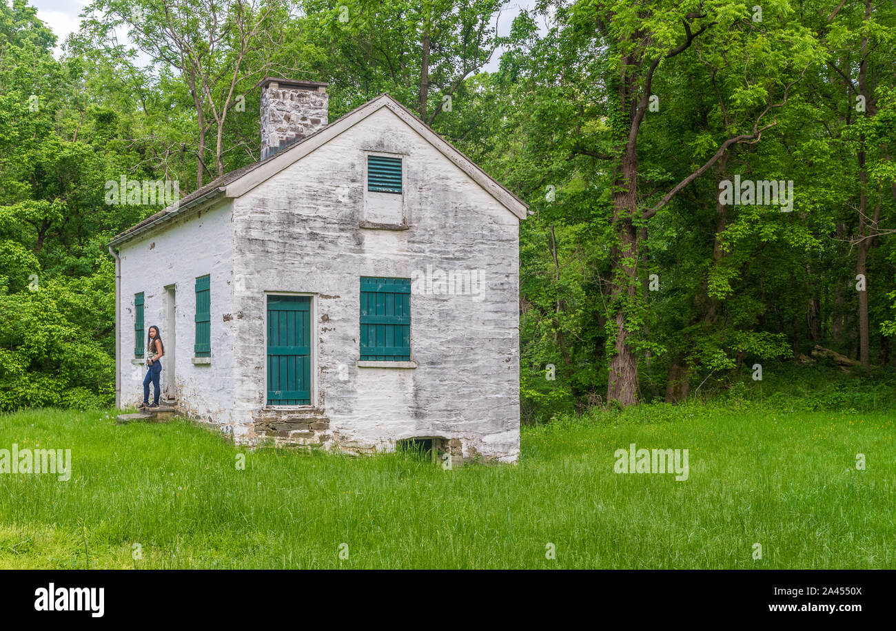 Donna in piedi da bloccare i detentori casa bianca con persiane verdi e porta a Chesapeake e Ohio Canal Foto Stock