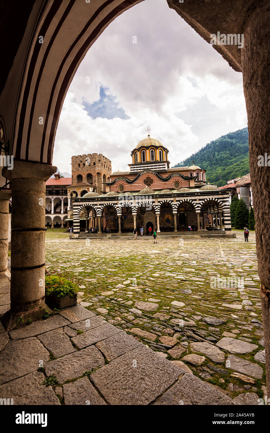 Rila, Bulgaria - 23 Giugno 2019: il Monastero di Rila, una delle principali destinazioni turistiche e sito UNESCO in Bulgaria, visto al di sotto di un arco Foto Stock