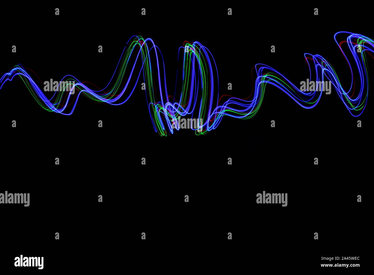 Una lunga esposizione fotografia di neon di colore in un astratto turbolenza, linee parallele configurazione contro uno sfondo nero. La pittura di luce la fotografia. Foto Stock