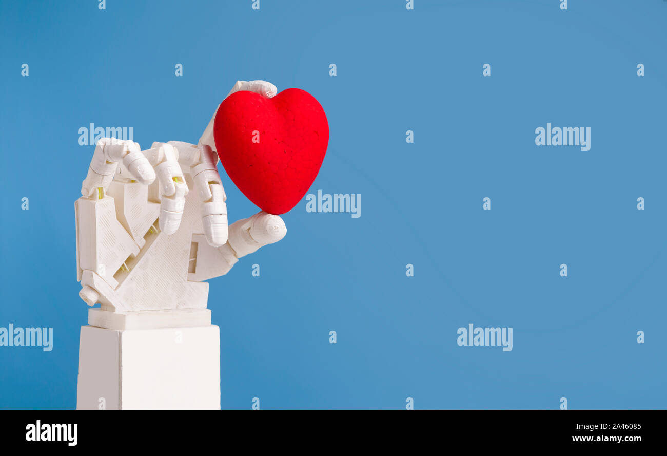 Medico robotico mano azienda cuore rosso, sfondo blu Foto Stock