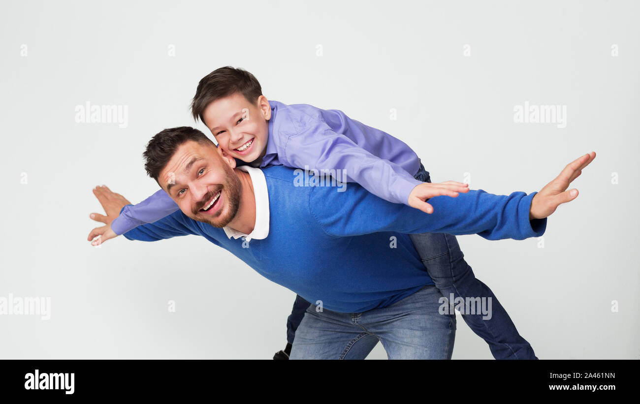 Uomo felice figlio di equitazione sul retro come volare sul piano Foto Stock