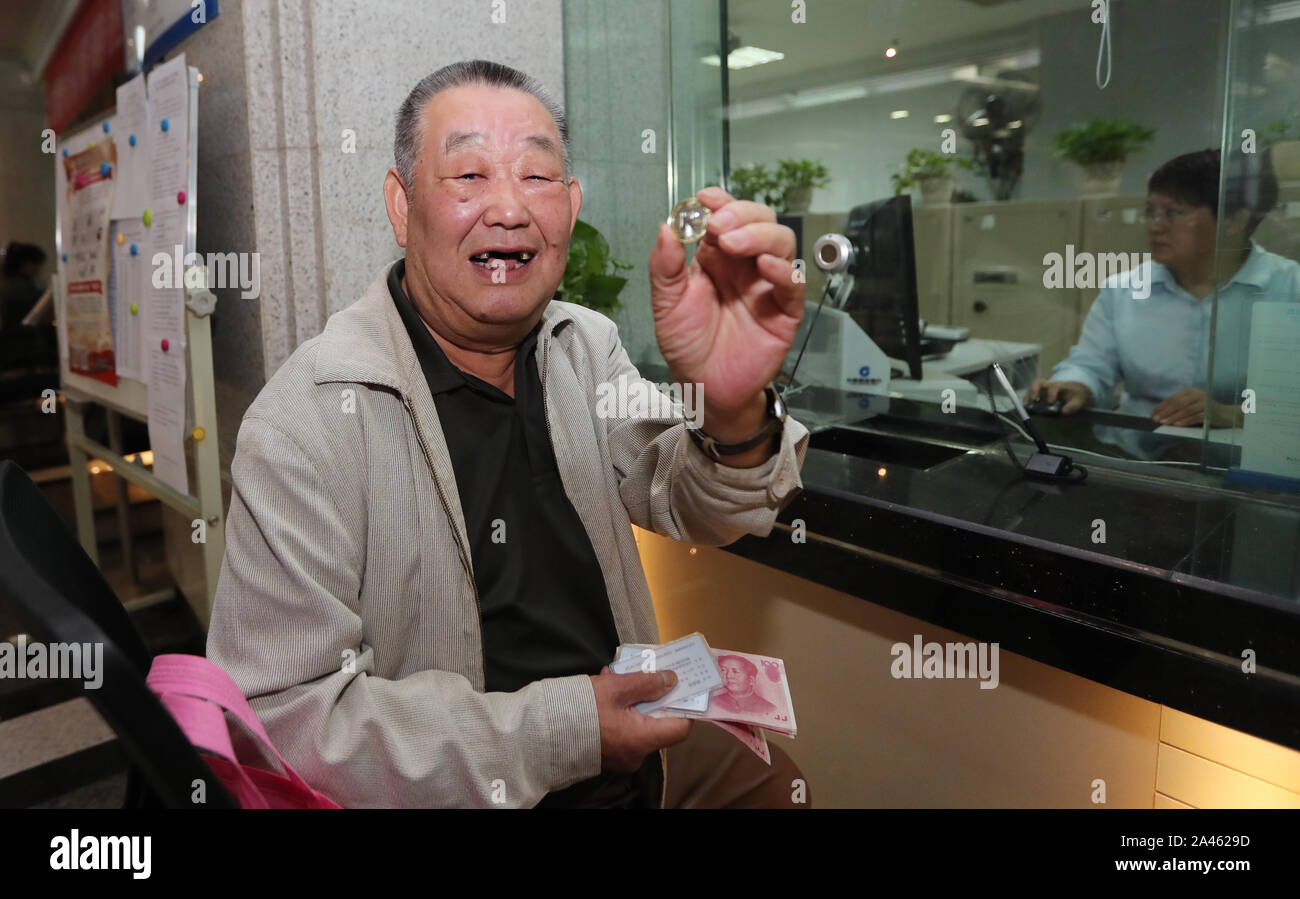 La vecchia moneta commemorativa amante, il fortunato primo, dimostra il suo guadagno di 10 Yuan moneta commemorativa con il tema del settantesimo giorno nazionale della Foto Stock