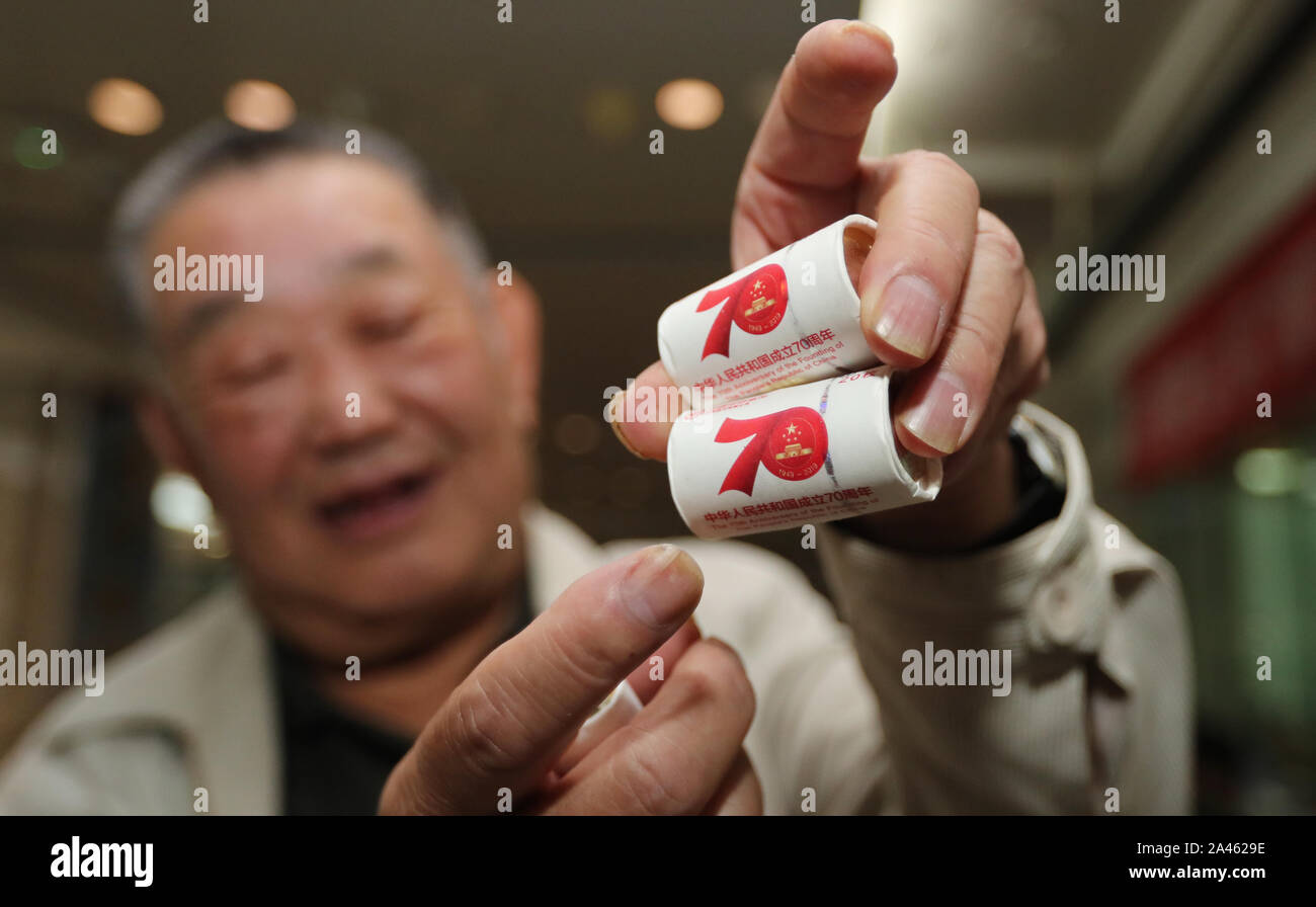 La vecchia moneta commemorativa amante, il fortunato primo, dimostra il suo guadagno di 10 Yuan moneta commemorativa con il tema del settantesimo giorno nazionale della Foto Stock