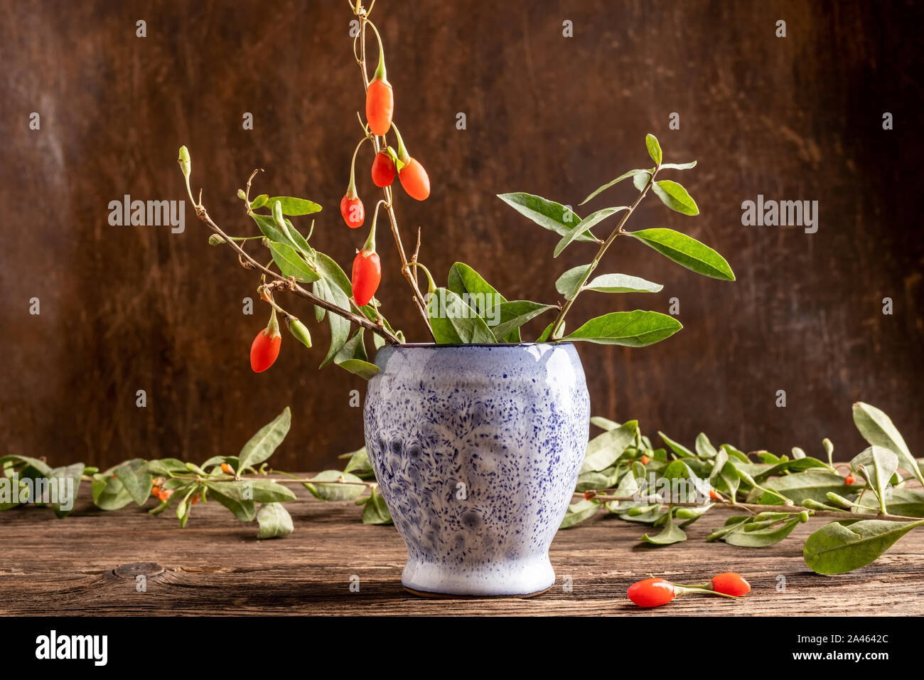 Fresh goji bacche con foglie su un tavolo di legno Foto Stock