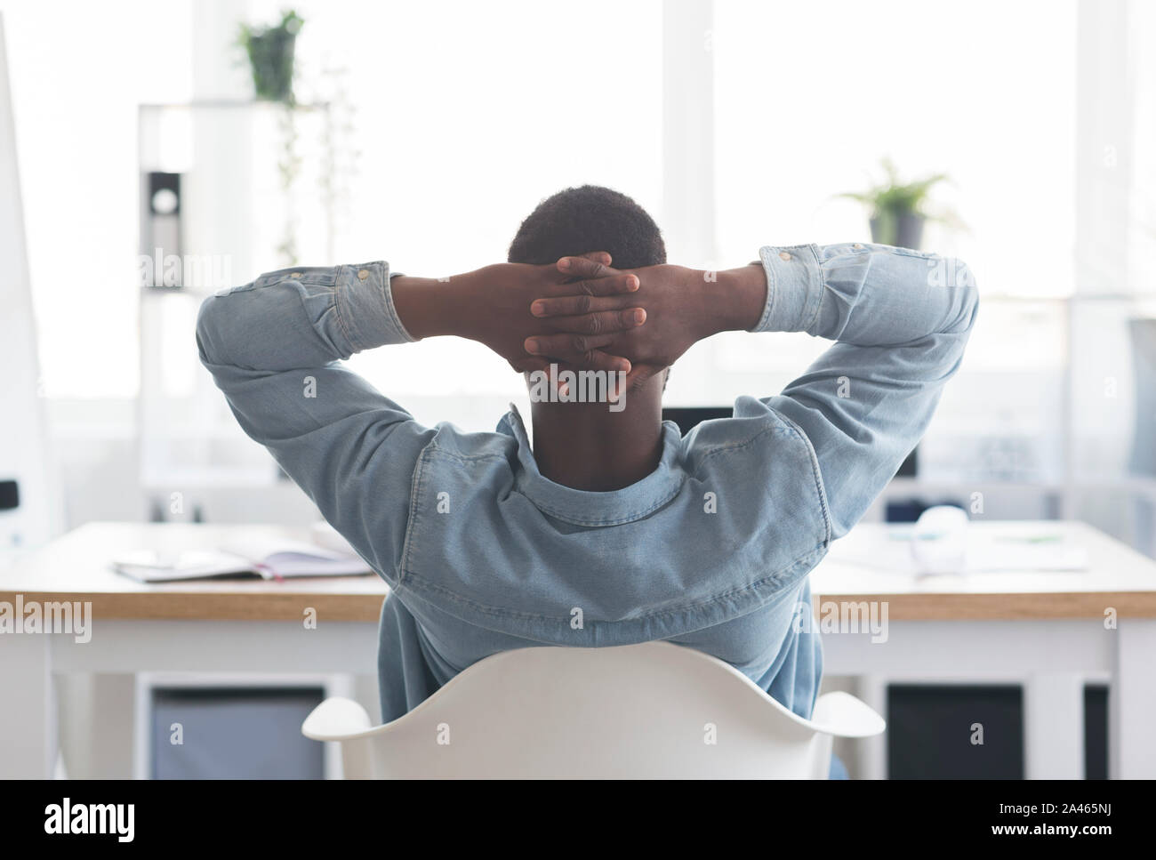 African American lavoratore in appoggio al lavoro, Pendente ritornare sulla sedia Foto Stock