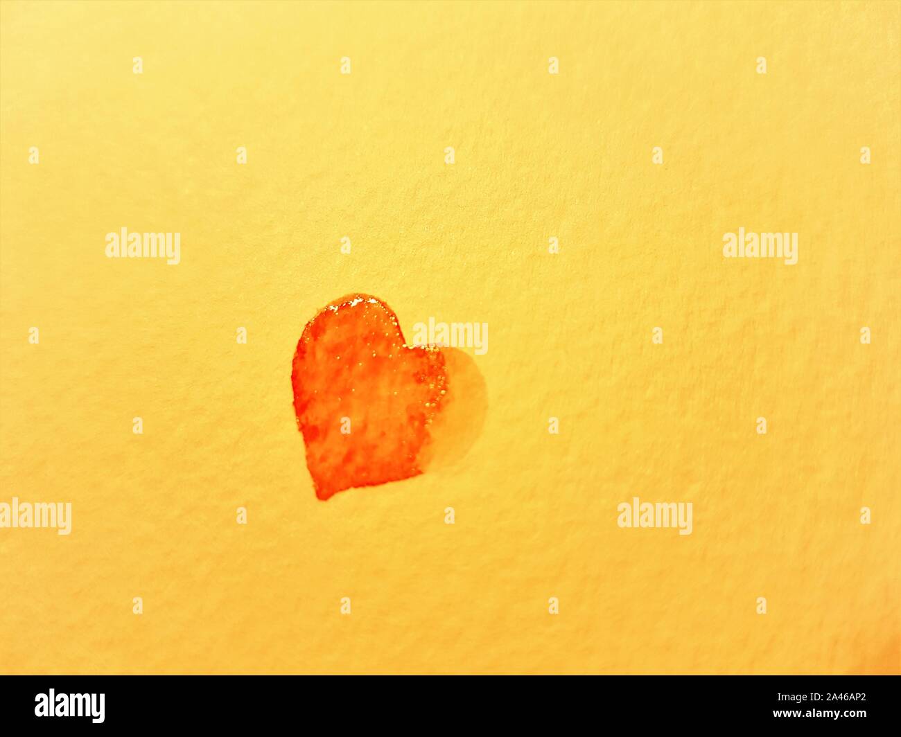 Rosso piccolo cuore bagnato dipinta su carta gialla. Spazio di copia Foto Stock