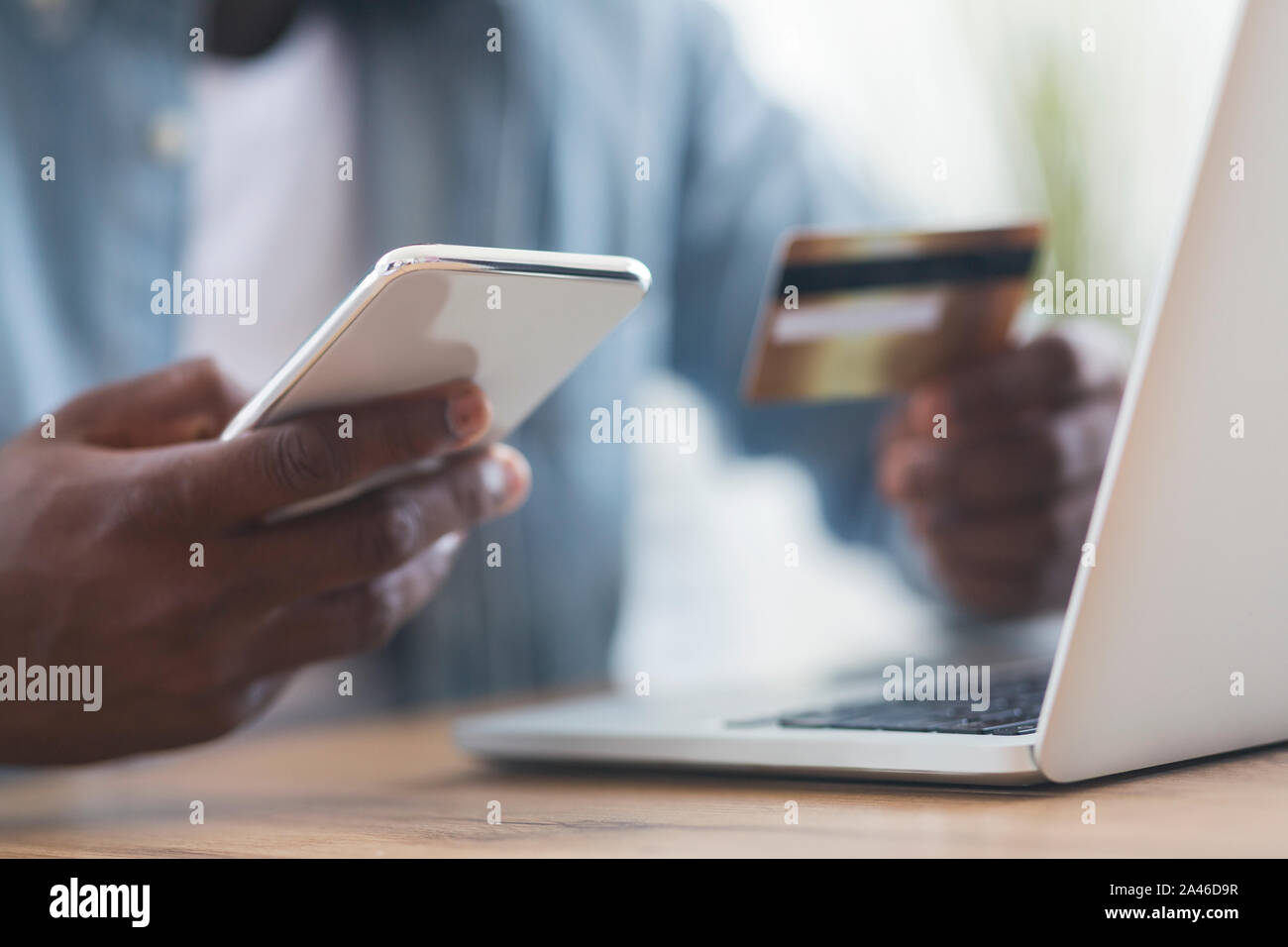 Irriconoscibile uomo nero utilizza lo smartphone e una carta di credito, shopping online Foto Stock