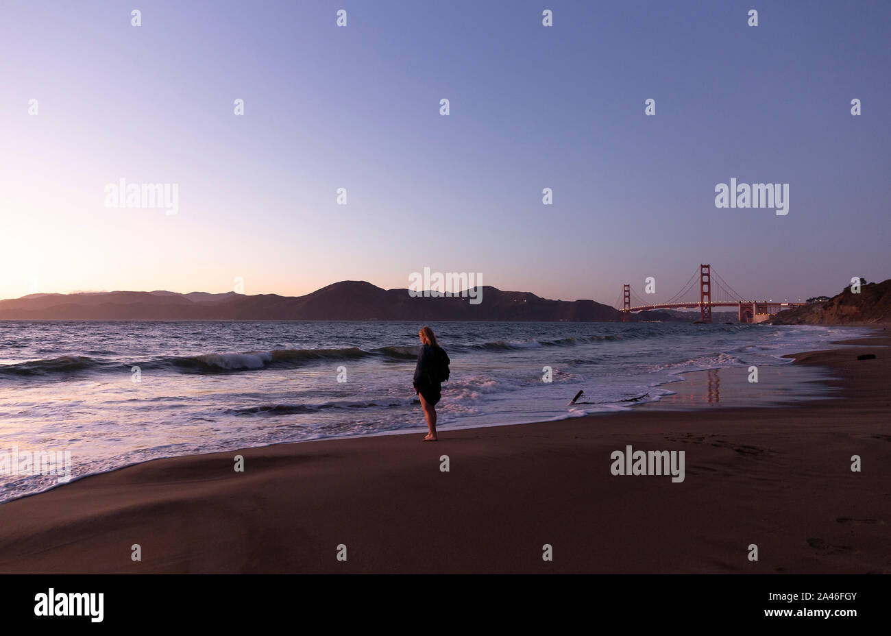 Donna Pagaiando su Baker spiaggia al tramonto, San Francisco, California, Stati Uniti Foto Stock