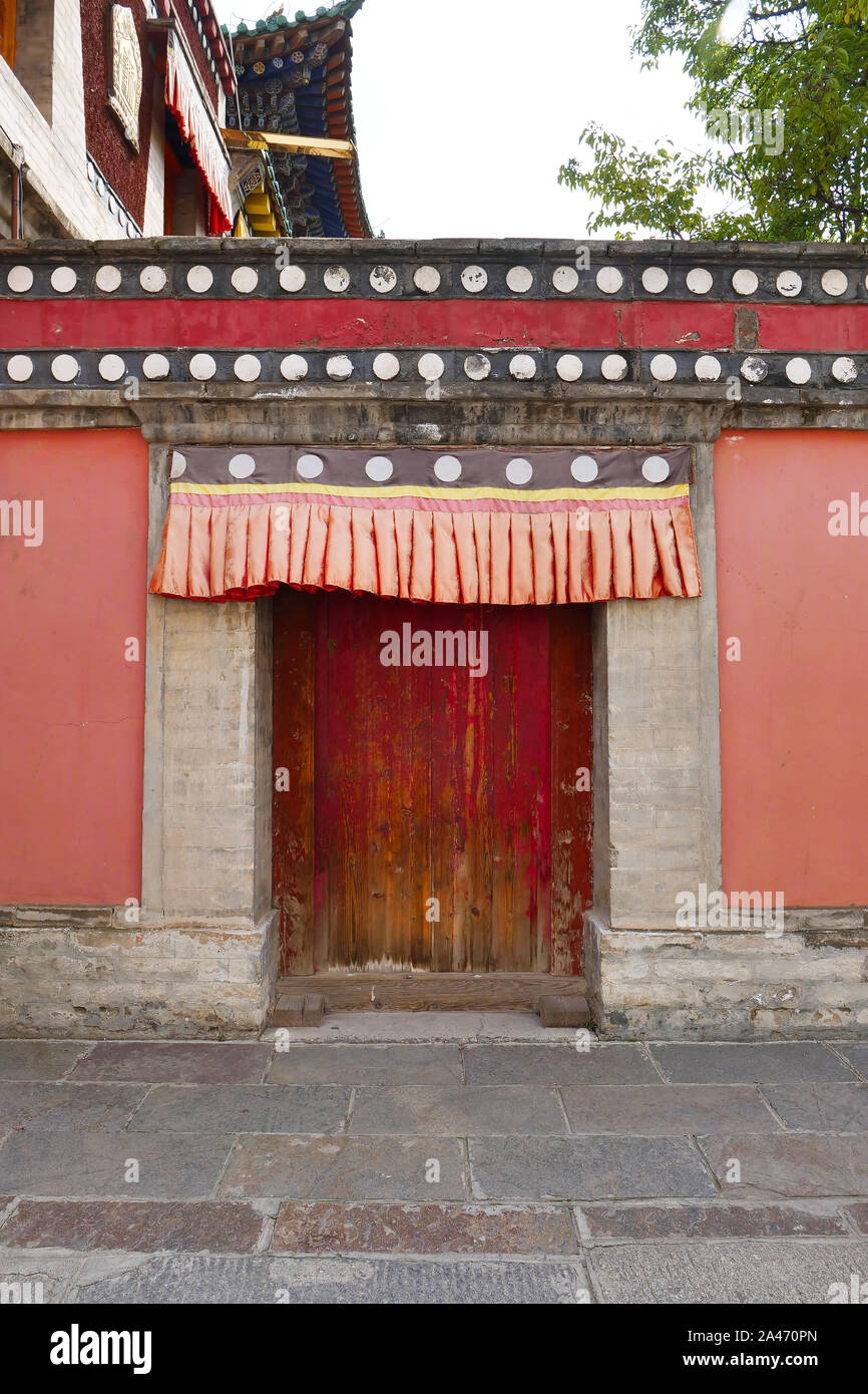 Retrò porta di legno e muro nel monastero Kumbum, Ta'er un tempio del buddismo tibetano monastero nella contea di Huangzhong, Xining Qinghai in Cina. Foto Stock