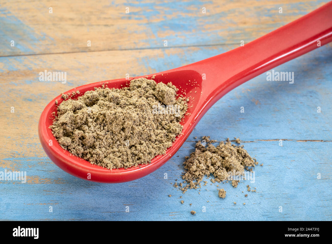 I semi di canapa proteine in polvere su un porcellanato cucchiaino contro blu dipinto di legno di grunge, Super supplemento Foto Stock