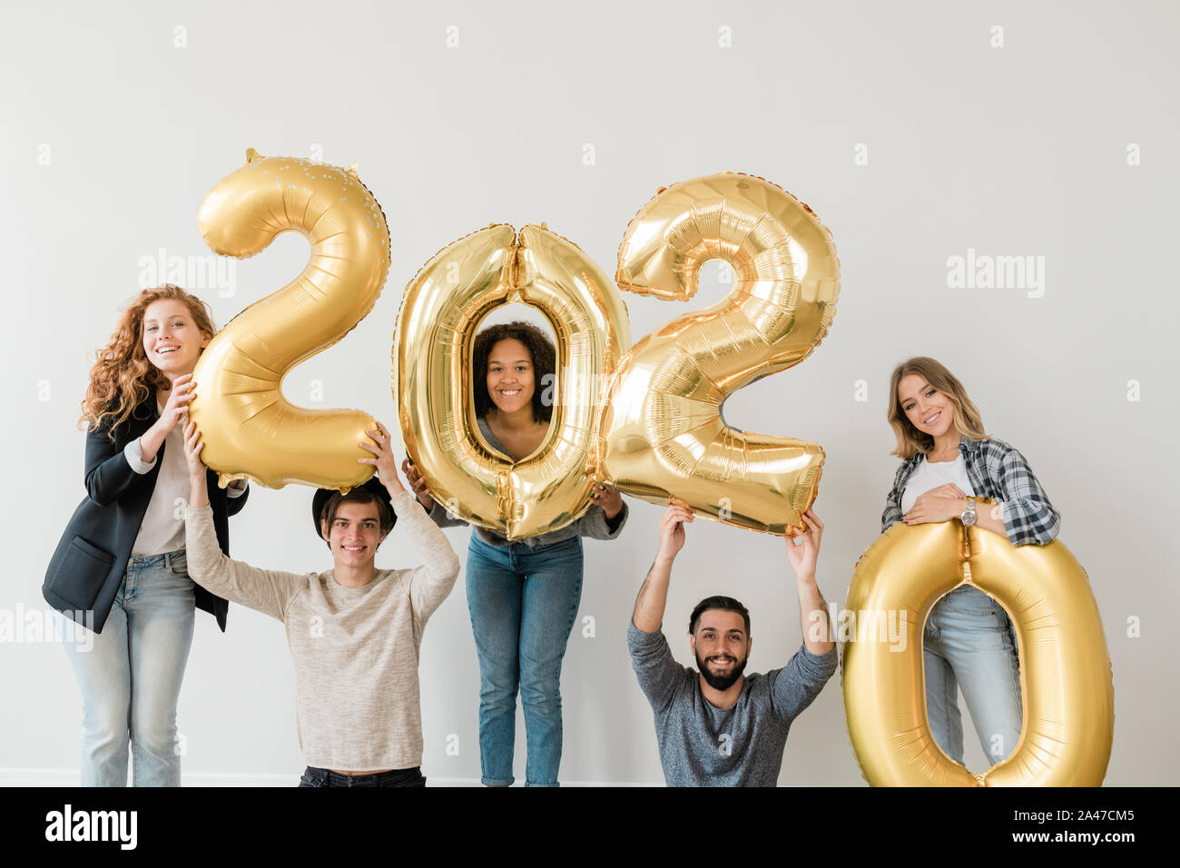 Felice gli adolescenti in piedi lungo il muro bianco mentre il numero dell'azienda del prossimo anno Foto Stock