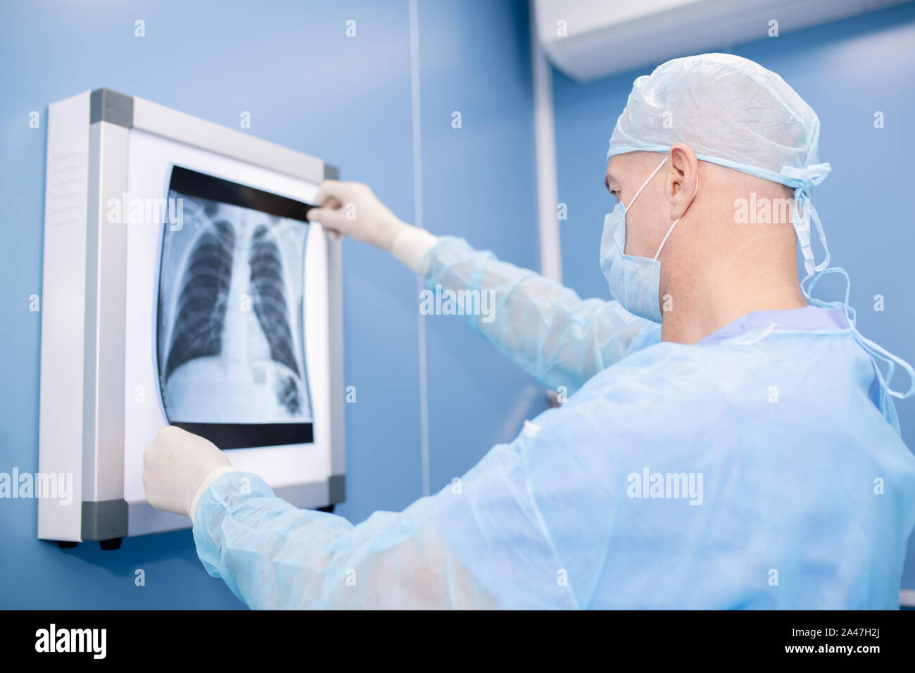 Professionista esperto in chirurgia uniforme e maschera guardando i polmoni x-ray Foto Stock