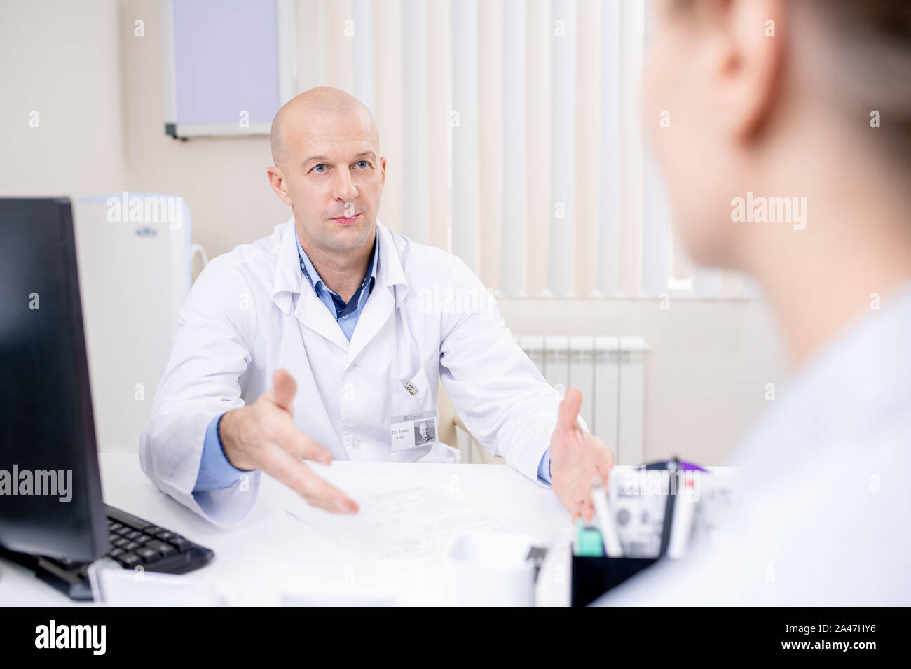 Bald fiducioso medico guardando il paziente mentre di dare consigli Foto Stock