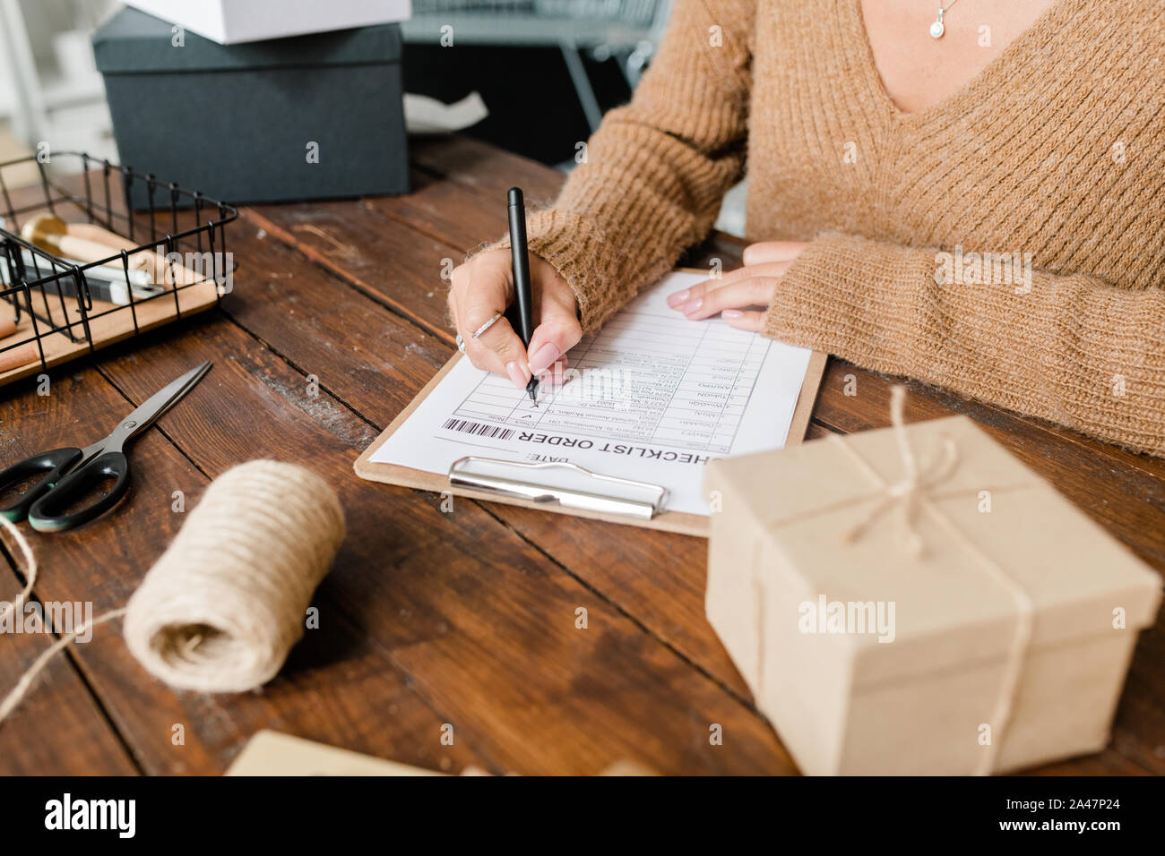 Cliente femmina in pullover mettendo le zecche di fronte la merce ordinata nella lista di controllo Foto Stock