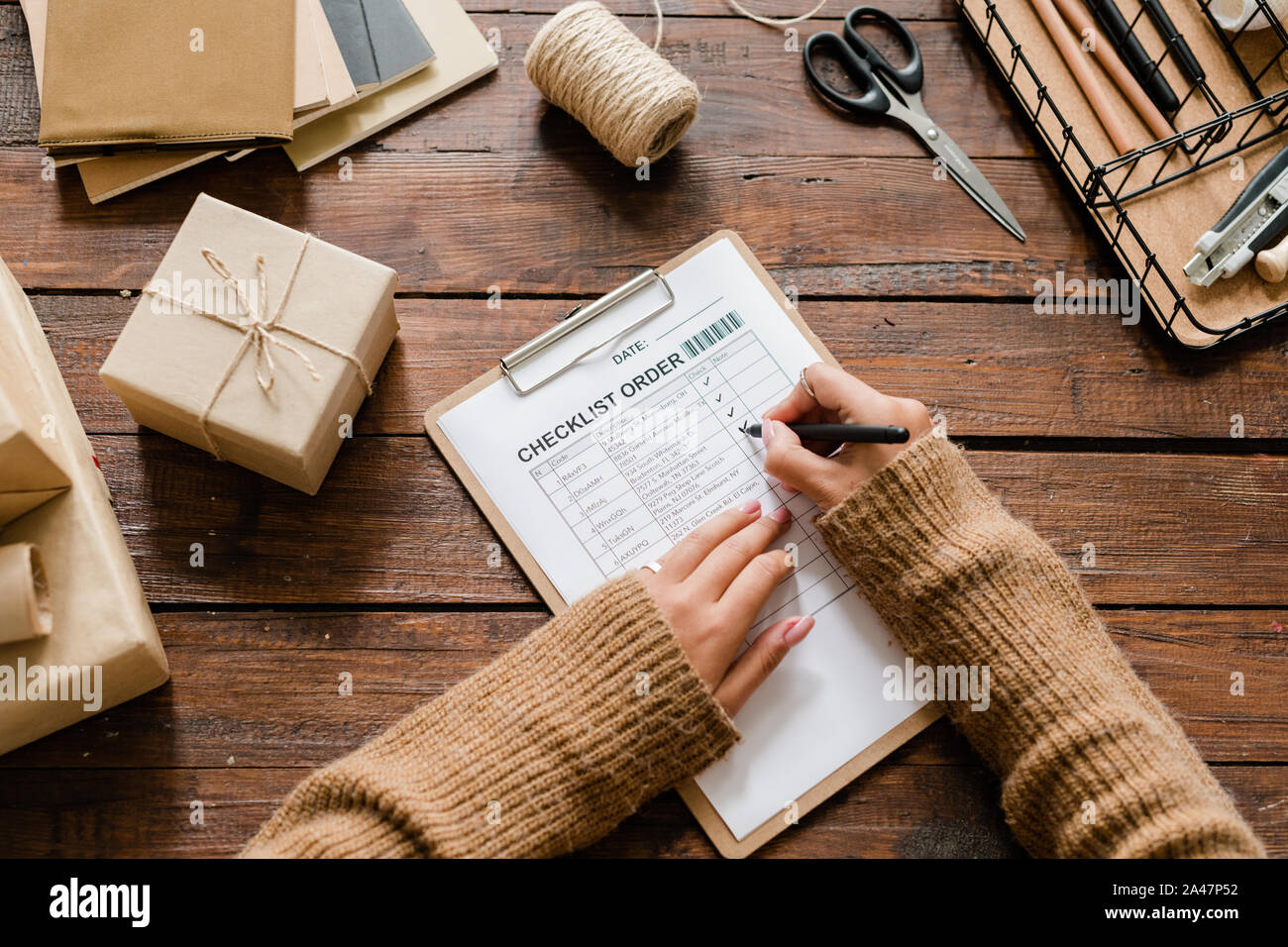 Vista delle mani del giovane femmina mettendo le zecche di fronte gli articoli ordinati in lista Foto Stock