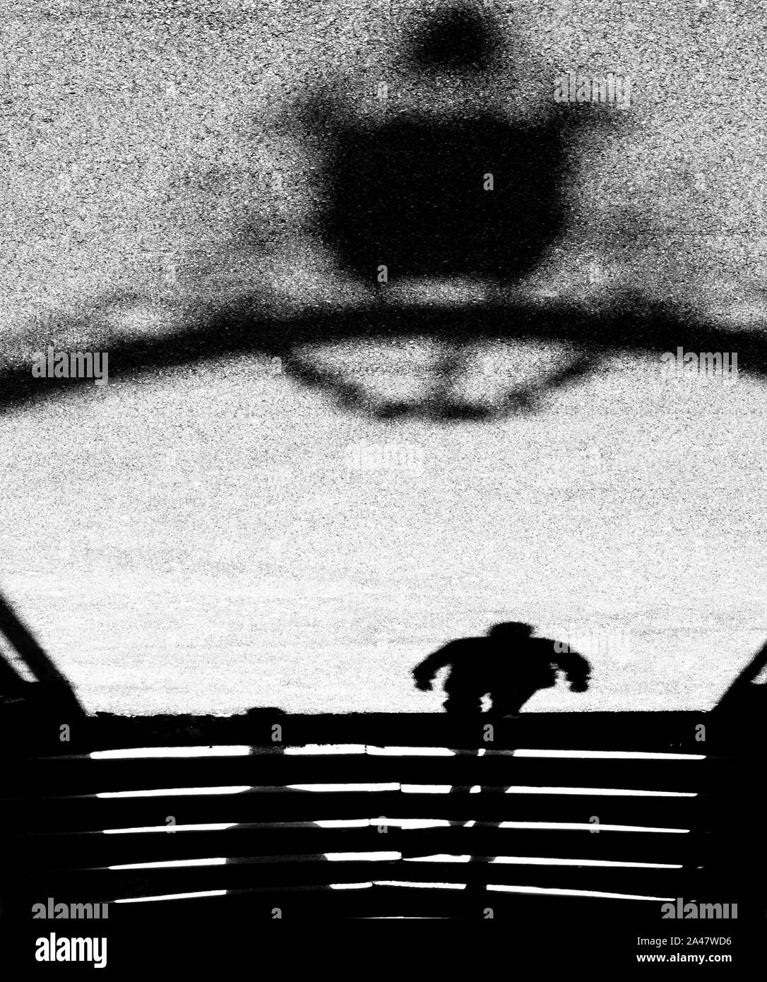 Ombre sfocate silhouette di un uomo a salire le scale e passando attraverso un enorme cancello vintage in bianco e nero Foto Stock