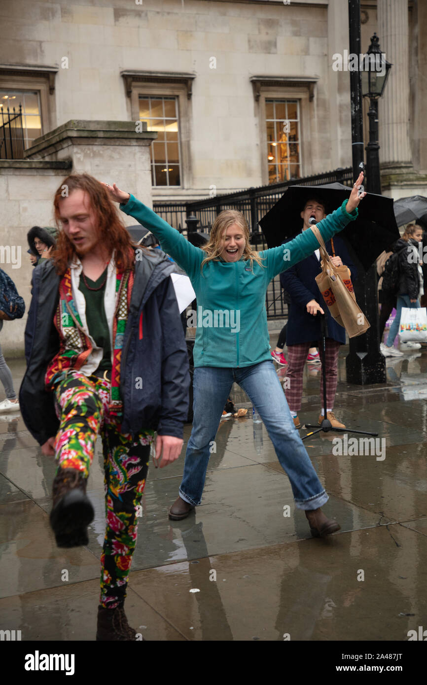 Londra, Regno Unito. Xii Ottobre 2019. I dimostranti e i turisti si vede ballare con la musica di un suonatore ambulante di Londra su Trafalgar Square durante la ribellione di estinzione due settimana di protesta a Londra. Credito: Joe Kuis / Alamy News Foto Stock