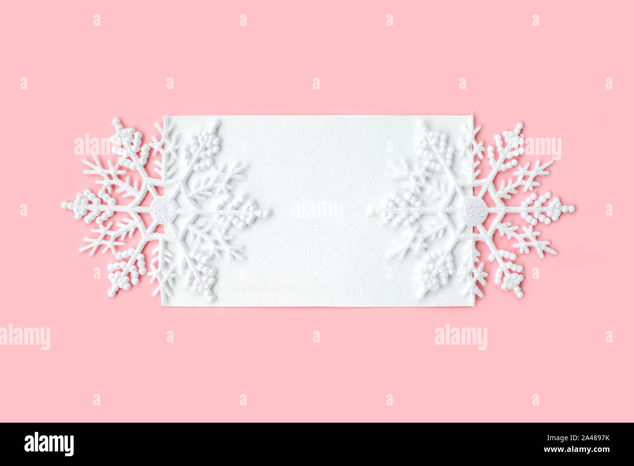 Libro bianco carta decorata con fiocchi di neve su sfondo rosa. Anno nuovo, Natale e il concetto d'inverno. Appartamento laico, vista dall'alto, copia gratuita dello spazio. Foto Stock