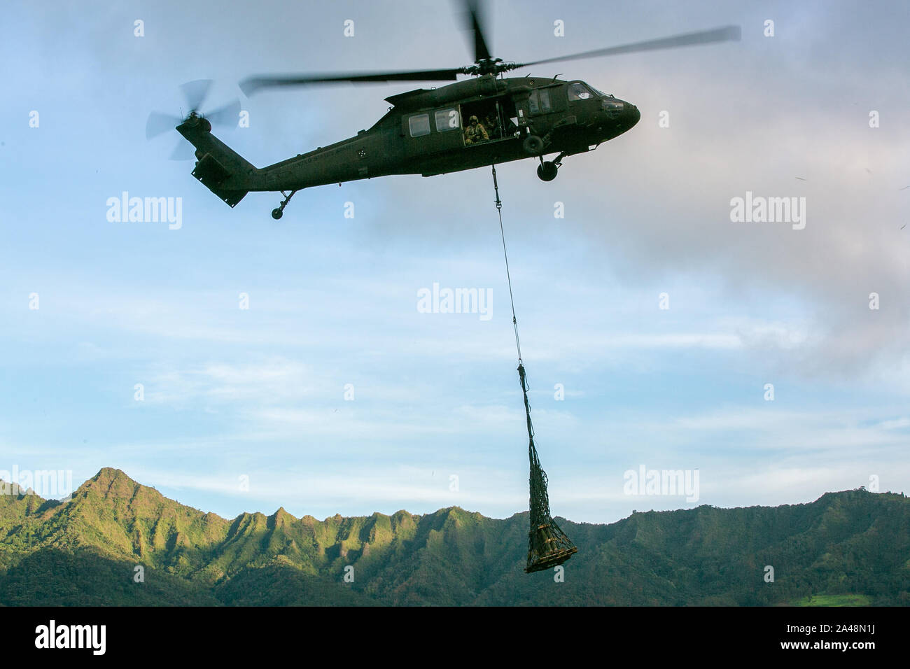 Stati Uniti Esercito UH-60 Black Hawk elicottero assegnato al 2° Battaglione, XXV Reggimento aviazione carichi di imbracatura 155mm giri prima di un live-fire air assault artiglieria raid su Schofield Barracks, Hawaii, Ottobre 10, 2019. Il venticinquesimo combattimento Brigata Aerea ha lavorato al fianco di Charlie batteria, 2° Battaglione, undicesimo campo Reggimento di Artiglieria sul primo live-fire air assault di M777 Obici mai condotto sull'isola di Oahu. (U.S. Foto dell'esercito da 1Lt. Ryan DeBooy) Foto Stock