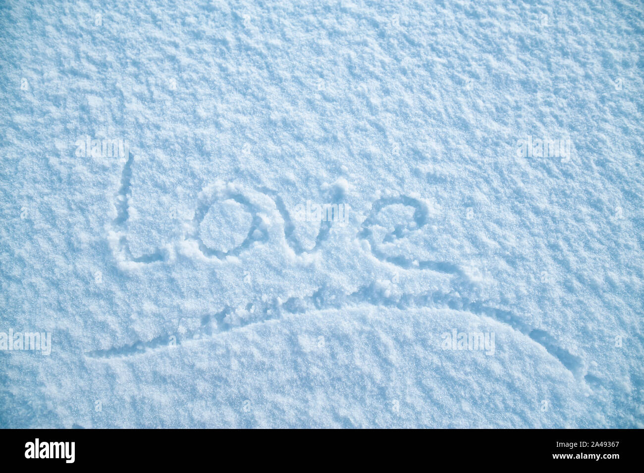 Manoscritte parola sottolineata 'amore' è scritto su bianco e soffice neve su un gelido inverno sera. Il giorno di San Valentino. Foto Stock