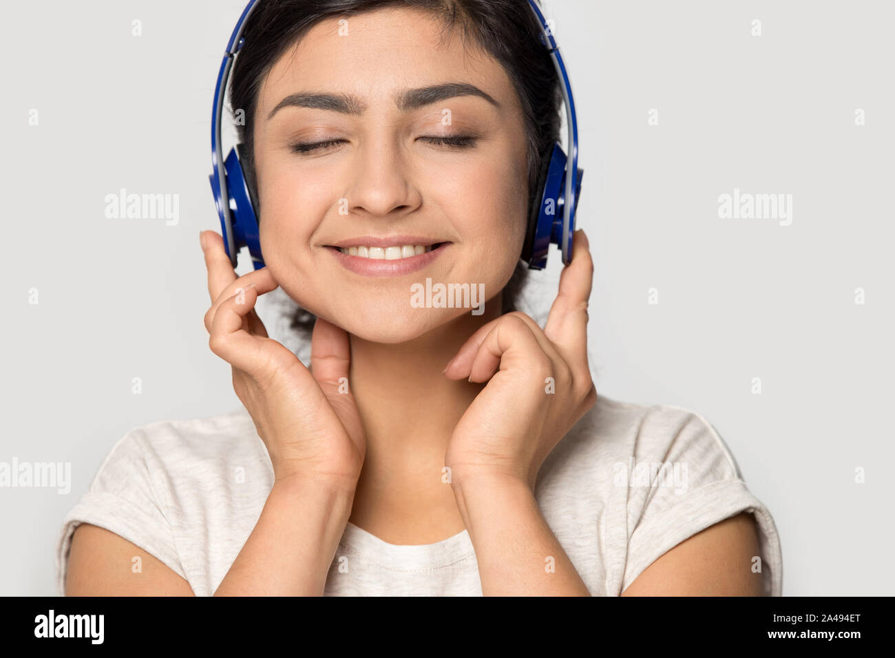 Sorridente ragazza etnica ascoltare musica con le cuffie Bluetooth Foto  stock - Alamy