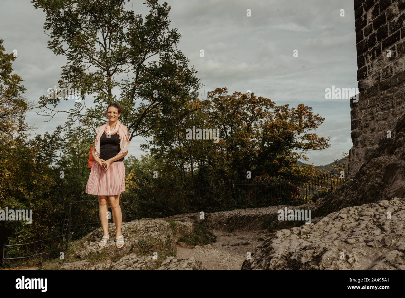 Una ragazza con un telefono sorridente e godendo di una soleggiata giornata di caduta in un parco, lifestyle immagine, effetto della pellicola Foto Stock