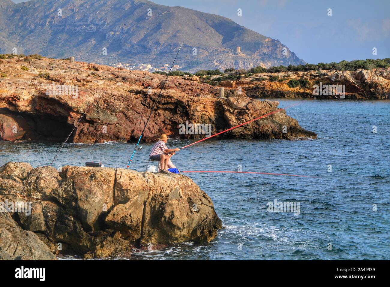 Isla Plana, Murcia, Spagna - 2 Ottobre 2019: pescatore e sua moglie la pesca sulle rocce di sera su Isla Plana spiaggia in una giornata di sole. Cartagena p Foto Stock