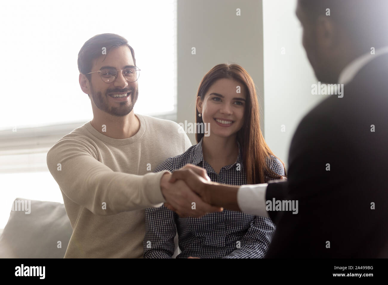 Entusiasta il marito millenario stringono le mani con African American broker maschio. Foto Stock
