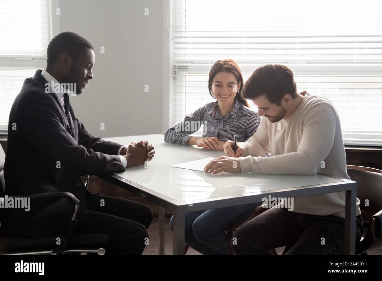 Sorridente venditore guardando i clienti felici firma contratto. Foto Stock