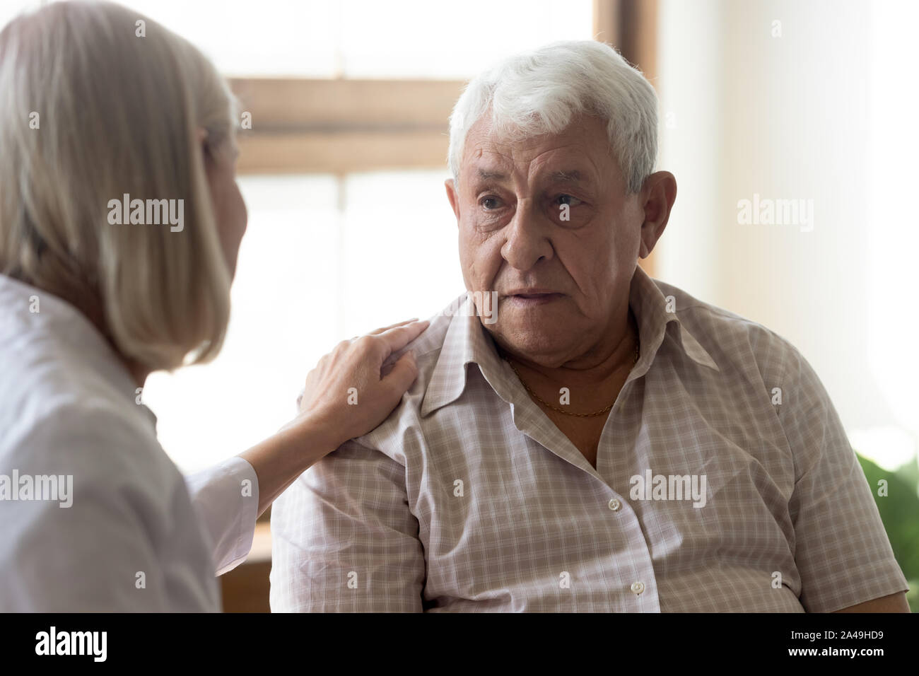70s uomo paziente e l'infermiera licenza pratico comunicante in ambienti interni Foto Stock