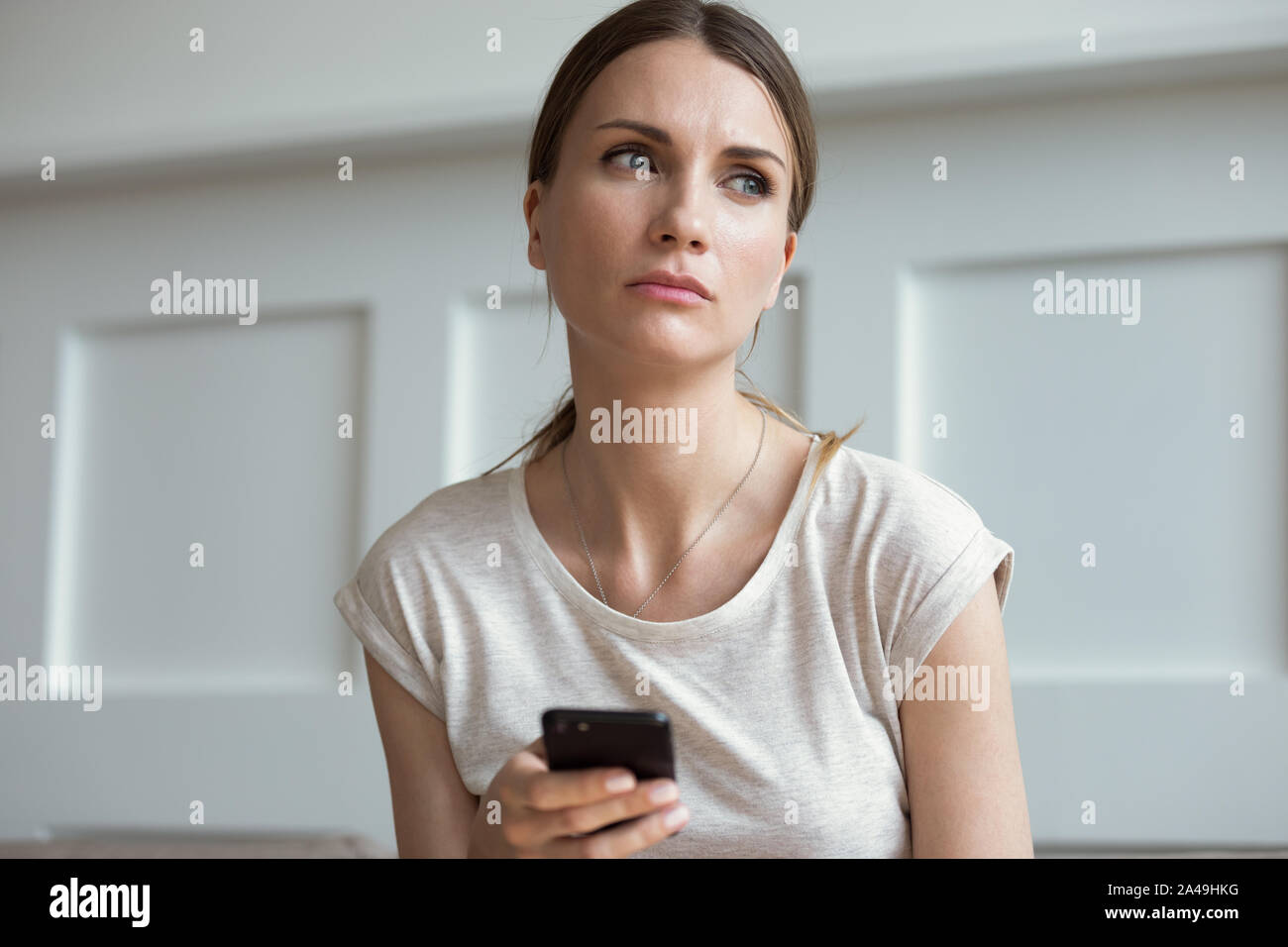 Triste donna tenendo lo smartphone in attesa chiamata da ragazzo si sente la gelosia Foto Stock