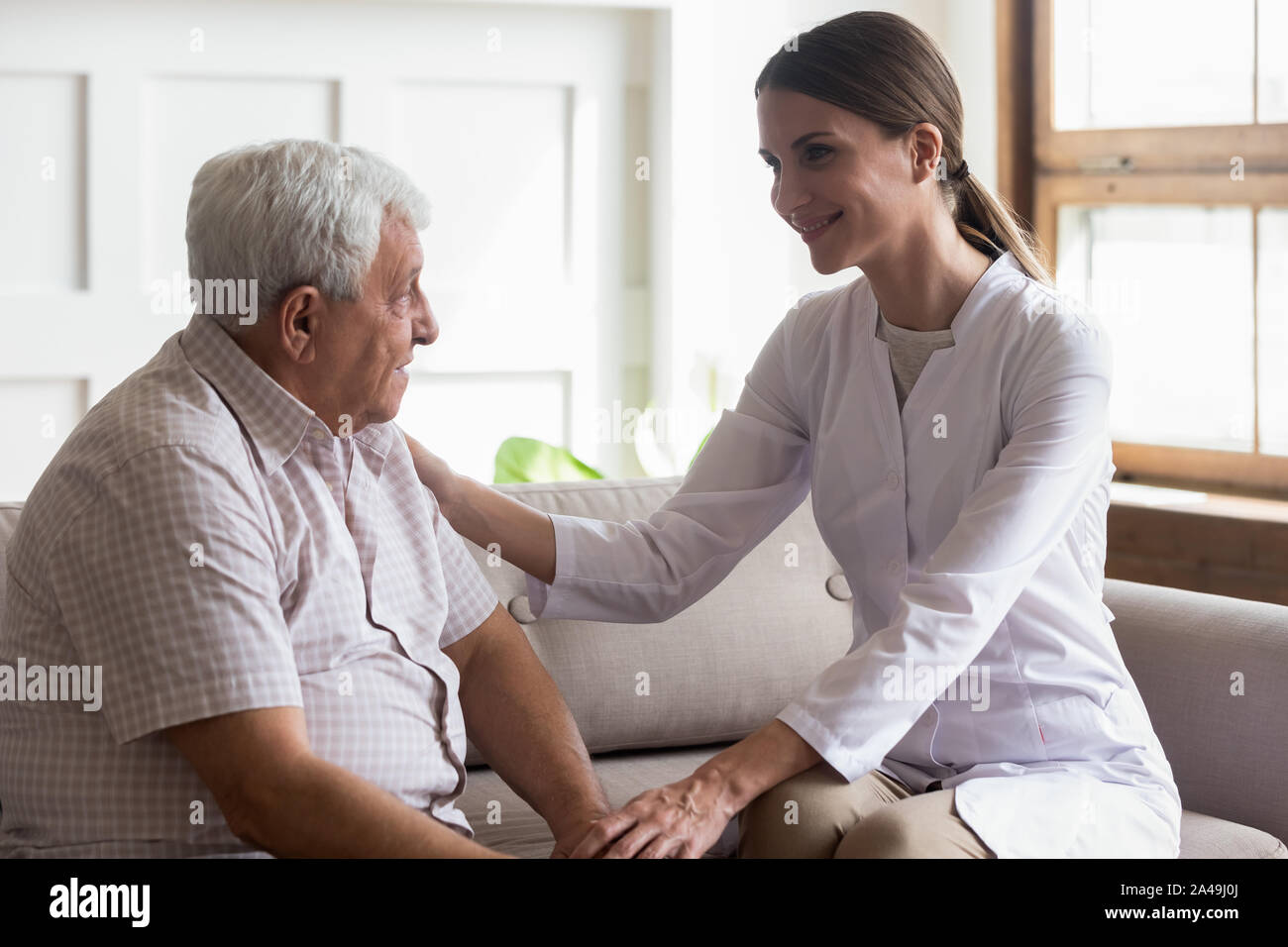 Il vecchio uomo paziente e attenta infermiere o operatore sanitario la comunicazione in ambienti interni Foto Stock