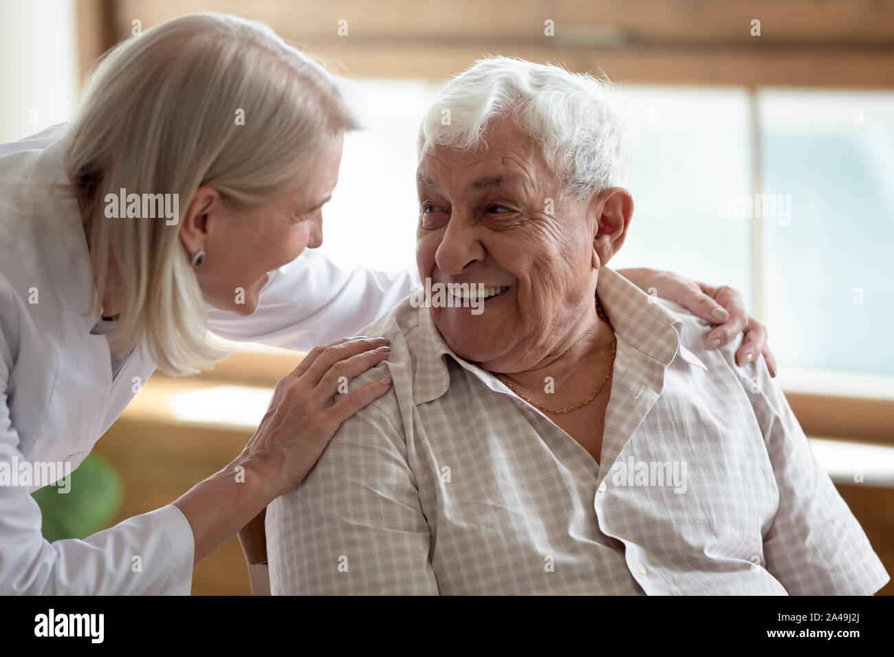 Cura l'infermiera parlando al paziente anziano 80s uomo Foto Stock