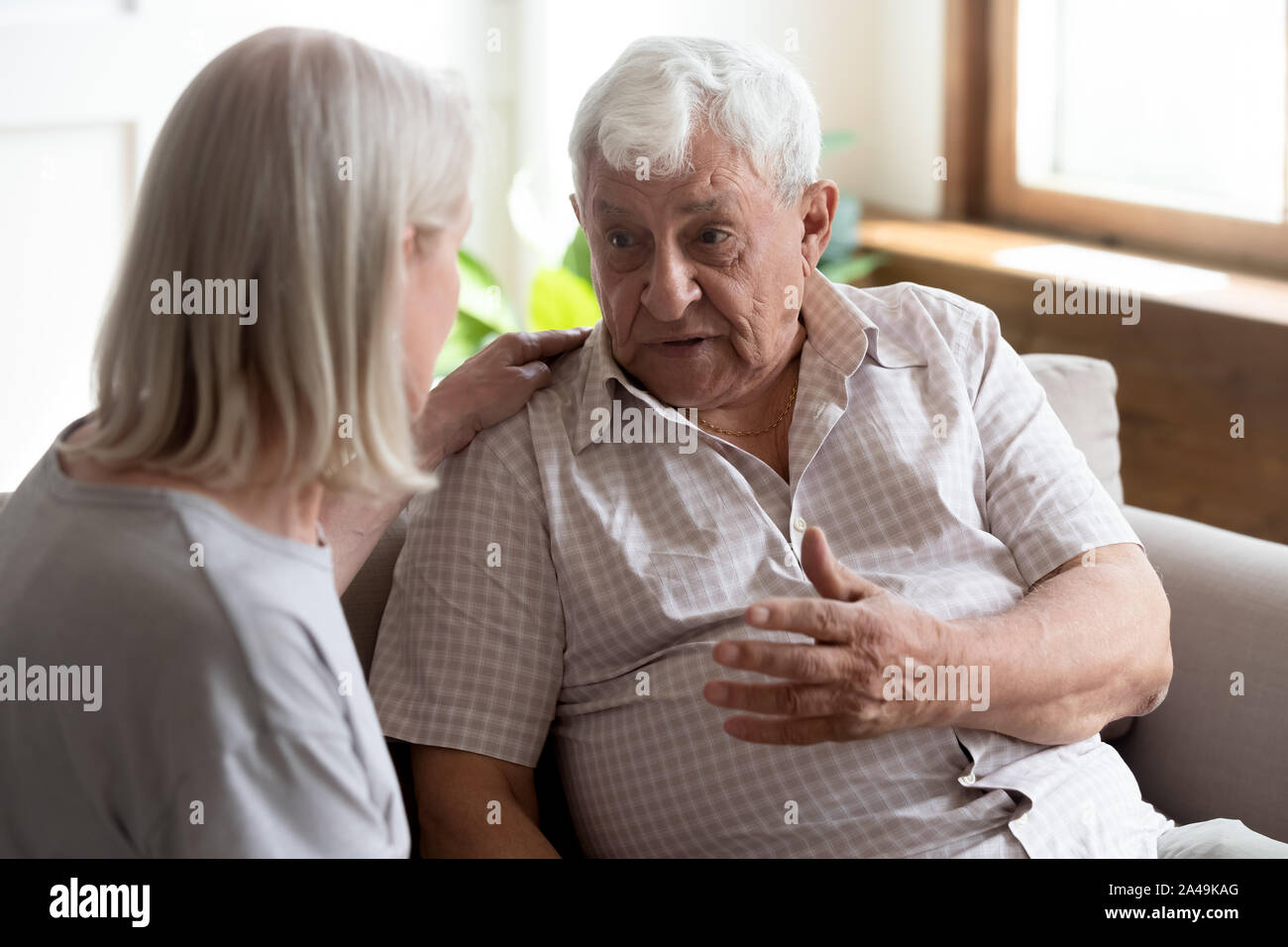 Infermiera geriatrica ascolta uomo anziano che mostra cura e supporto Foto Stock