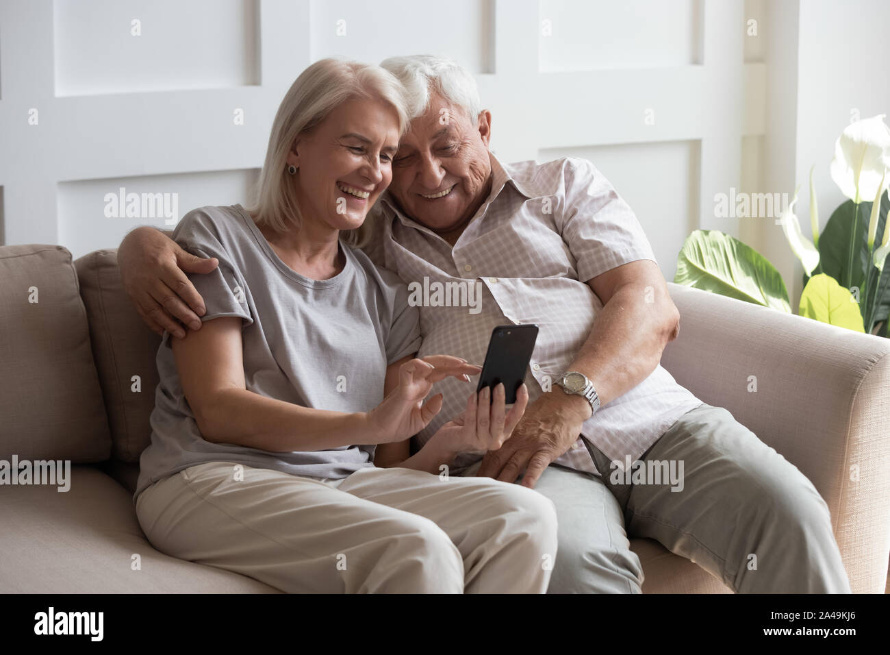 Anziani nonno e la nonna trascorrere del tempo divertendosi utilizza lo smartphone Foto Stock