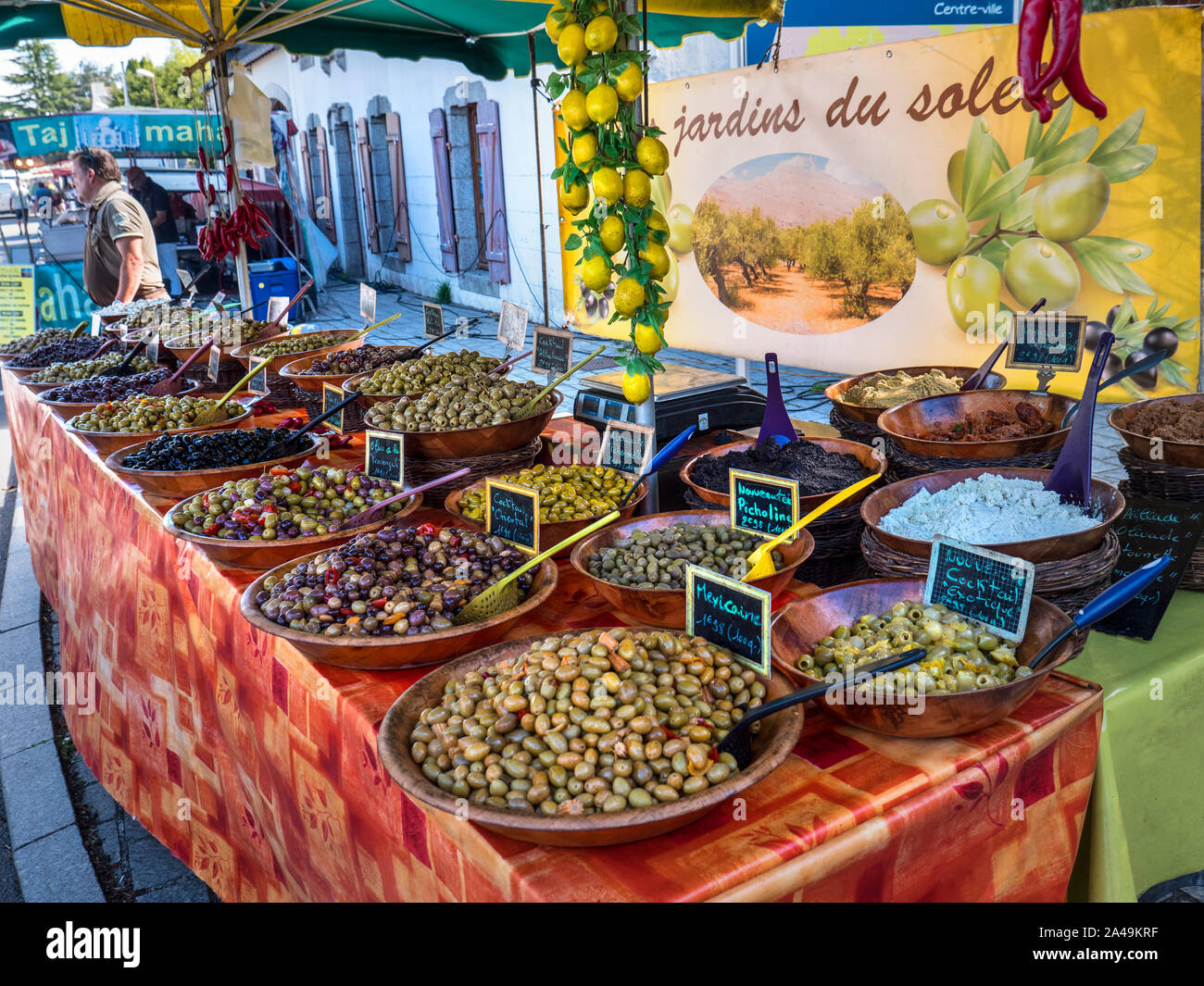 Il bretone del mercato e di stallo titolare di stallo la vendita di una varietà di olive sane sul display, in ciotole di legno Jardins du Soleil Moelan Sur Mer Bretagna Francia Foto Stock