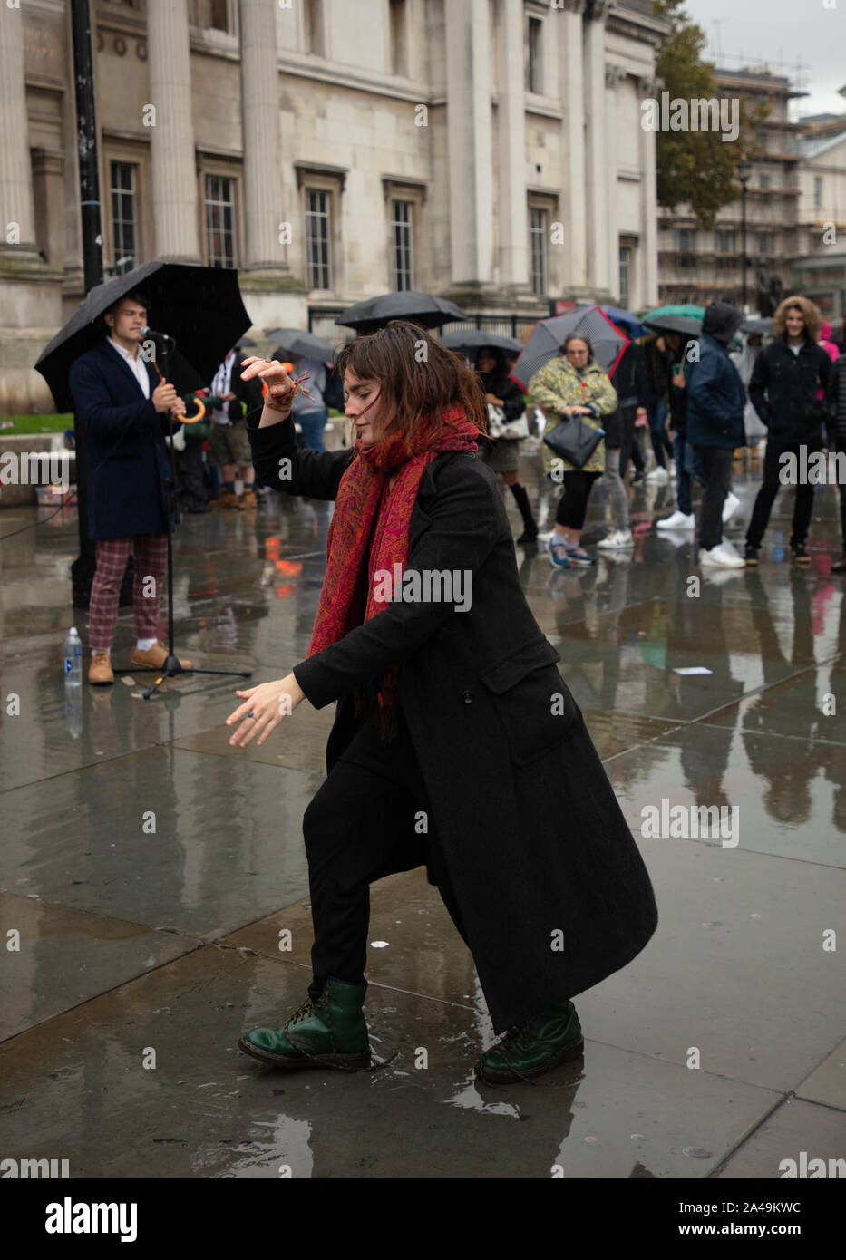 Londra, Regno Unito. 12 ottobre 2019. I manifestanti hanno visto ballare sotto la pioggia con la musica di un busker londinese su Trafalgar Square a Londra. Credit: Joe Kuis / Alamy News Foto Stock