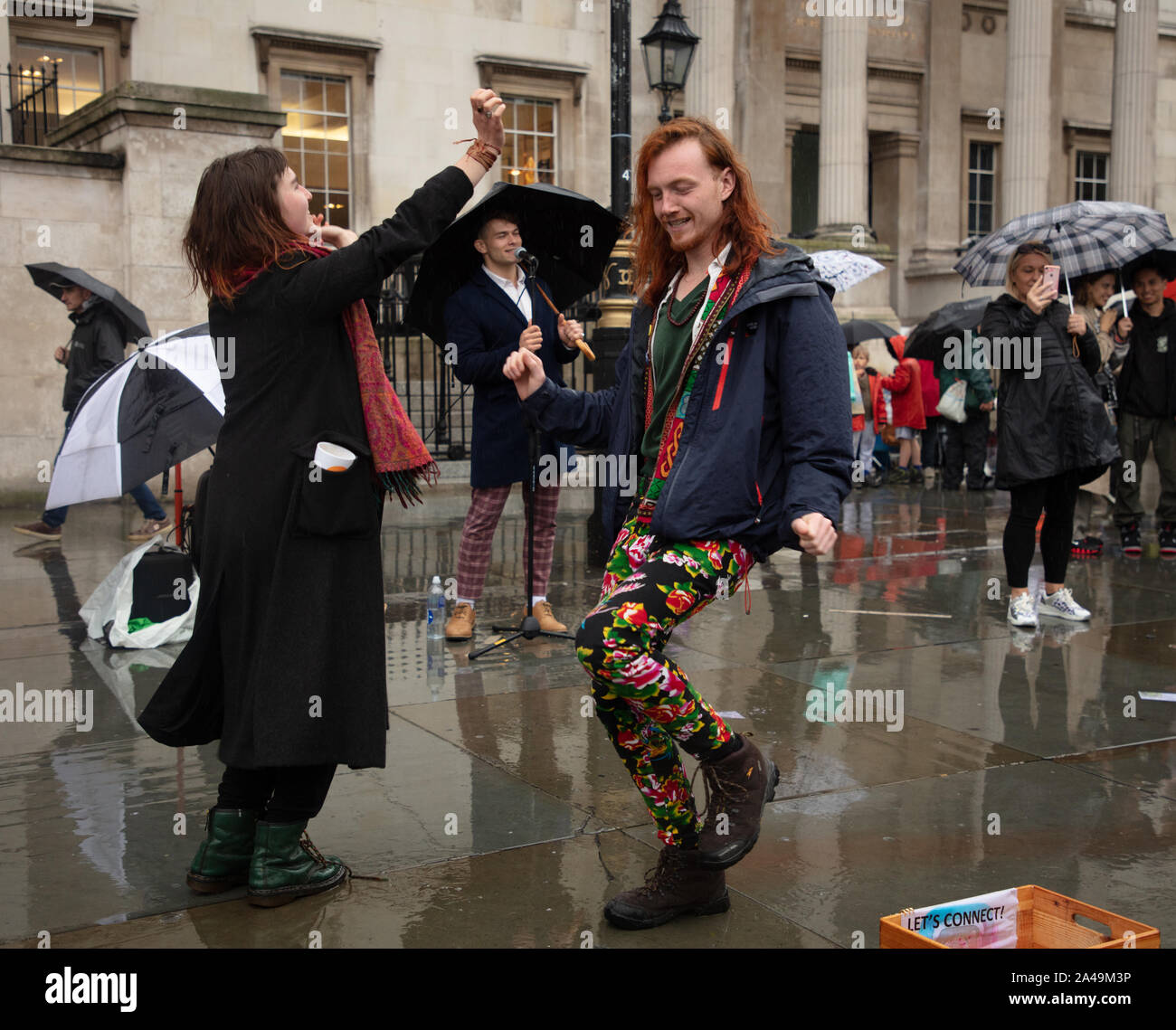 Londra, Regno Unito. 12 ottobre 2019. I manifestanti hanno visto ballare sotto la pioggia con la musica di un busker londinese su Trafalgar Square a Londra. Credit: Joe Kuis / Alamy News Foto Stock