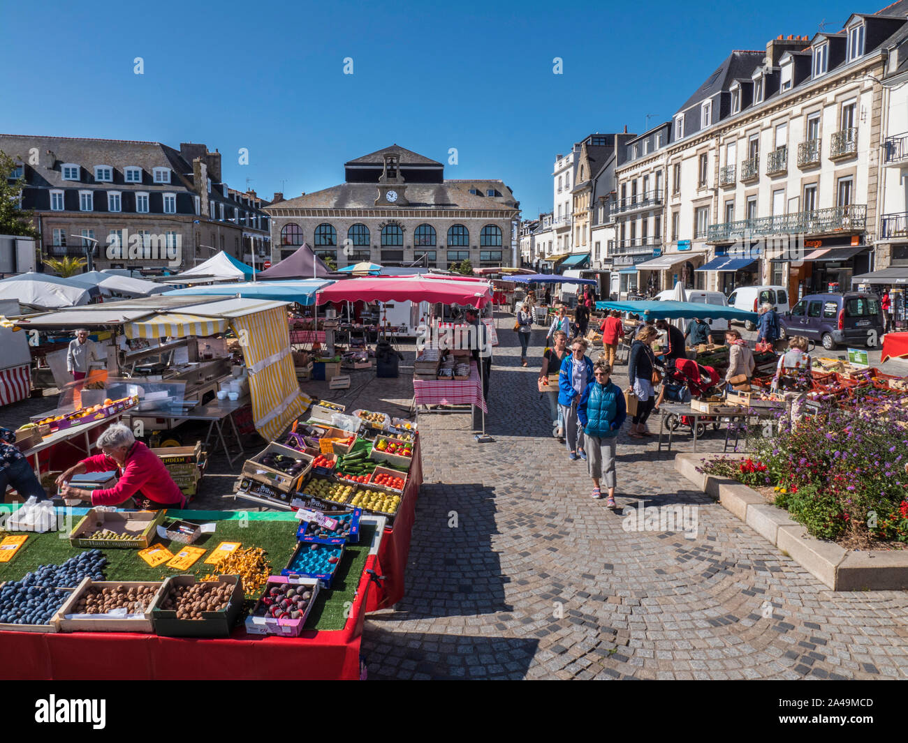 CONCARNEAU MERCATO ALL'APERTO Francese fresco produrre in vendita al giorno di mercato in piazza e al mercato al coperto Les Halles in background Concarneau Bretagna Francia Foto Stock