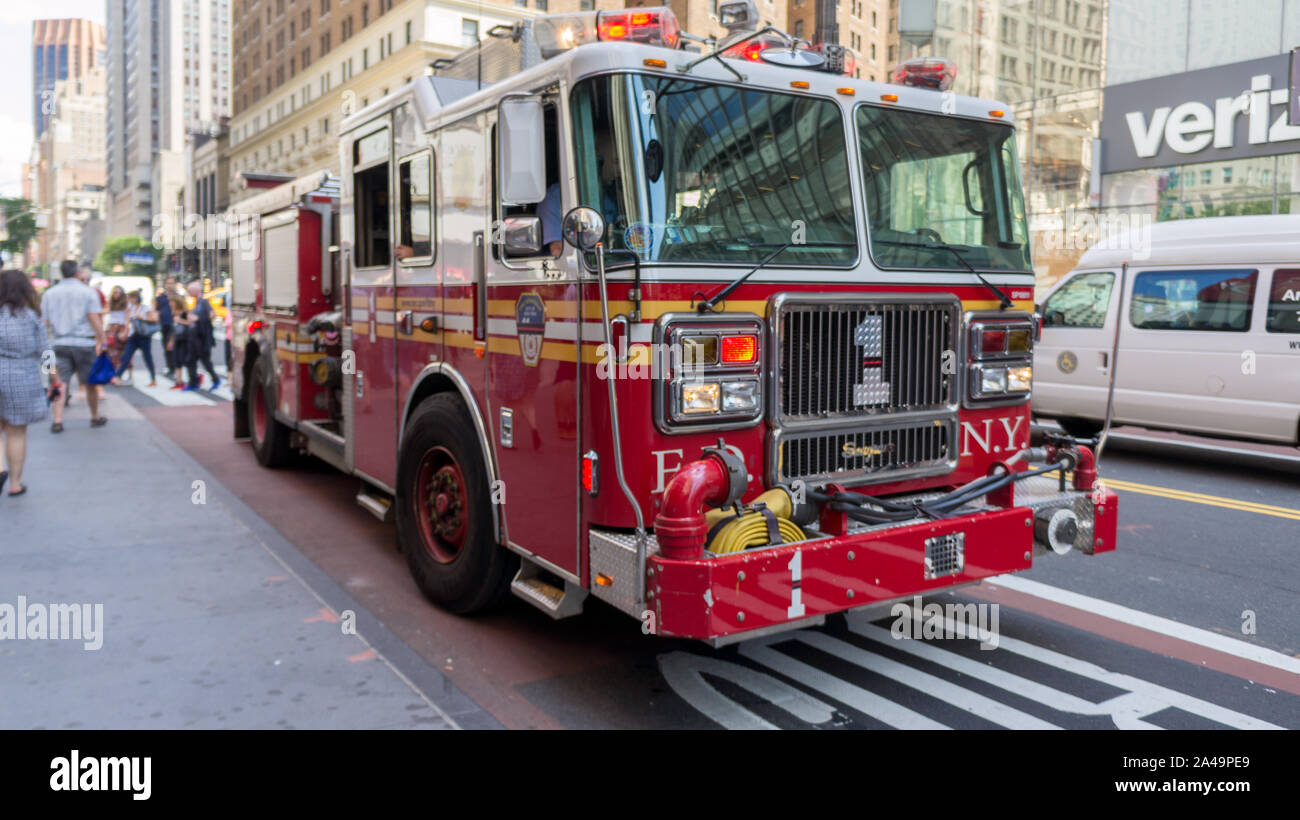 Firetruck rosso in New York nella parte anteriore dell'Empire State building e altri edifici iconici Foto Stock