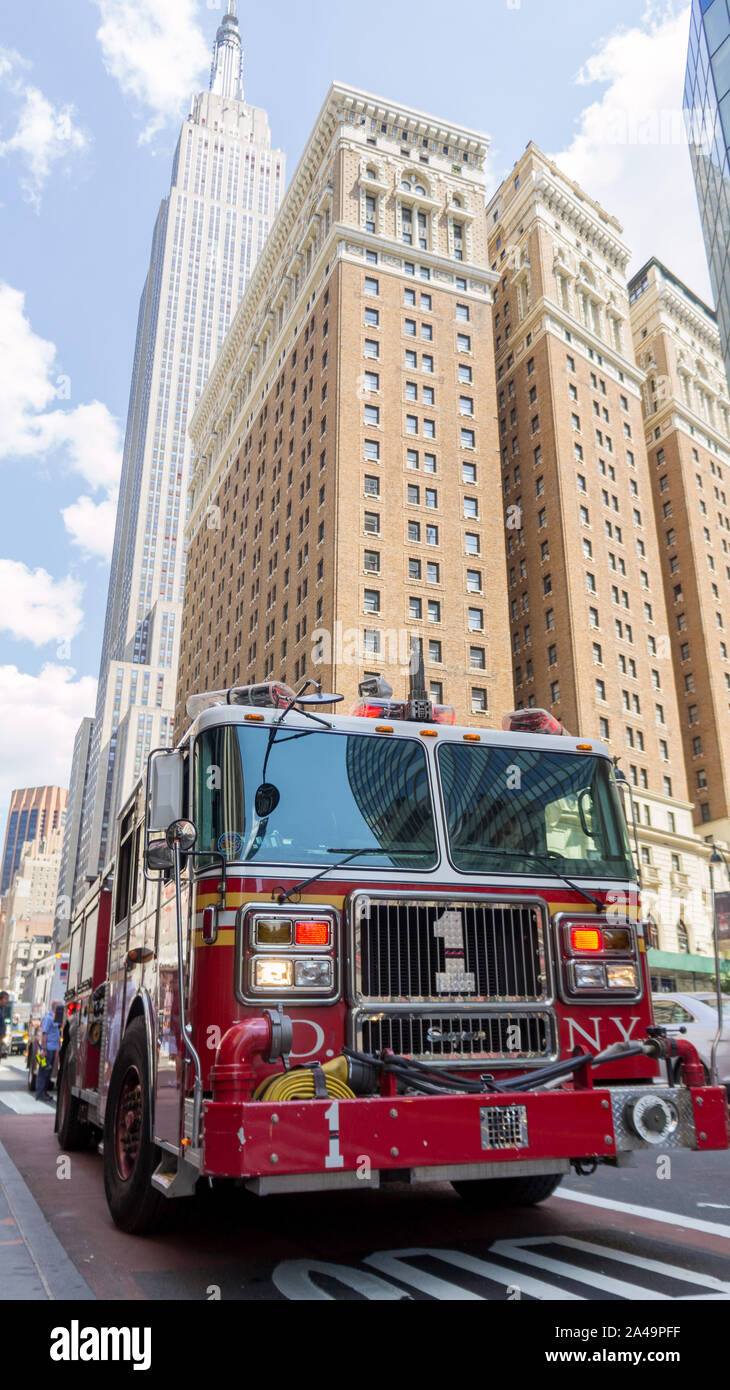 Firetruck rosso in New York nella parte anteriore dell'Empire State building e altri edifici iconici Foto Stock